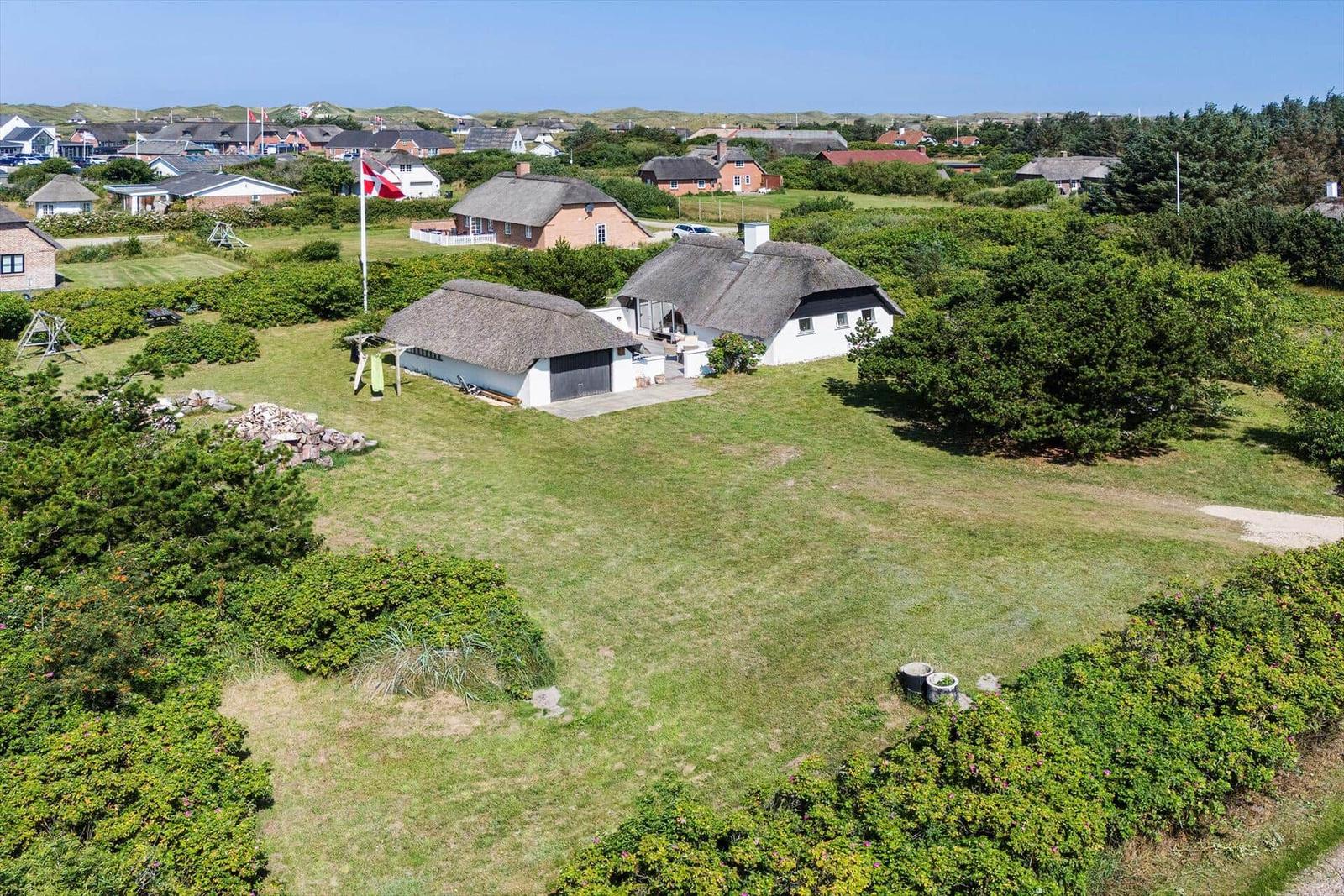 Haus mit Strohdach und großem Garten. Blick auf die Umgebung mit weiteren Häusern.