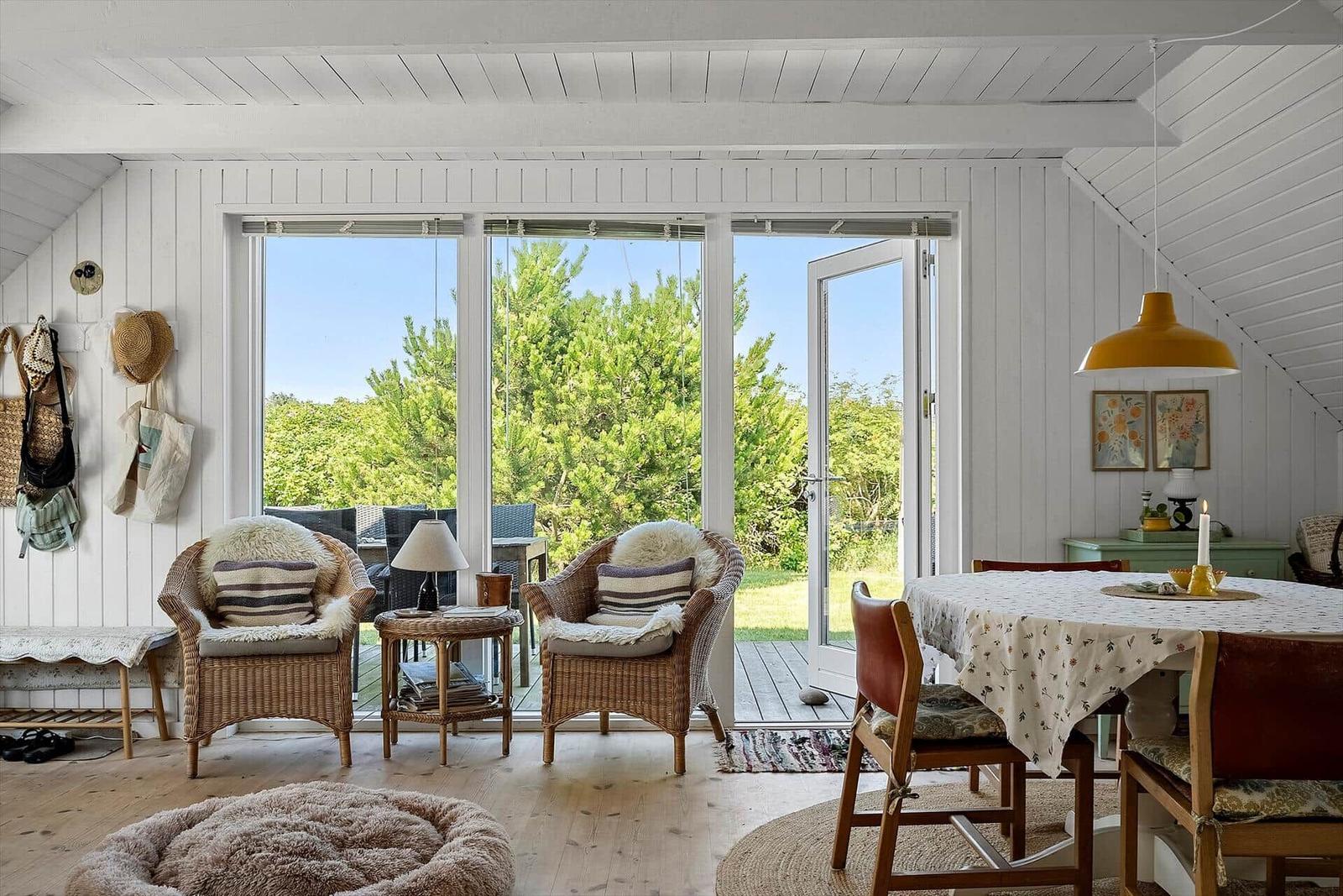 Wohnraum mit Sitzgelegenheiten, Tisch und Blick auf Garten