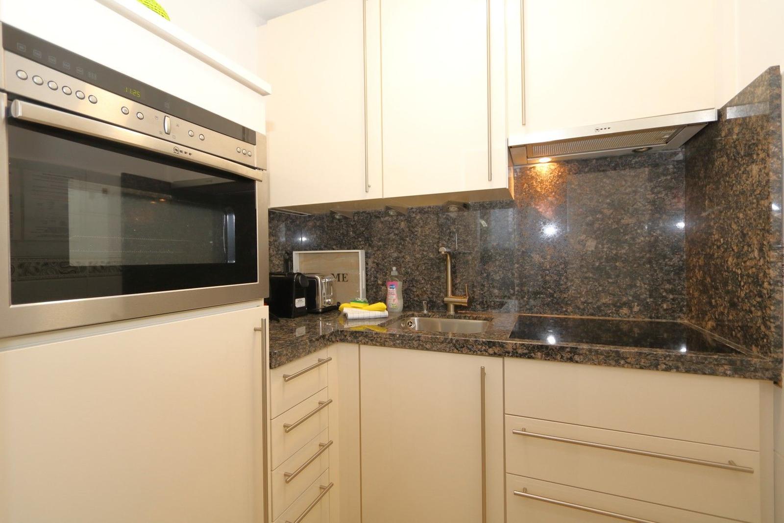 Küche mit Edelstahlherd, Granit-Arbeitsplatte und Unterschränken.