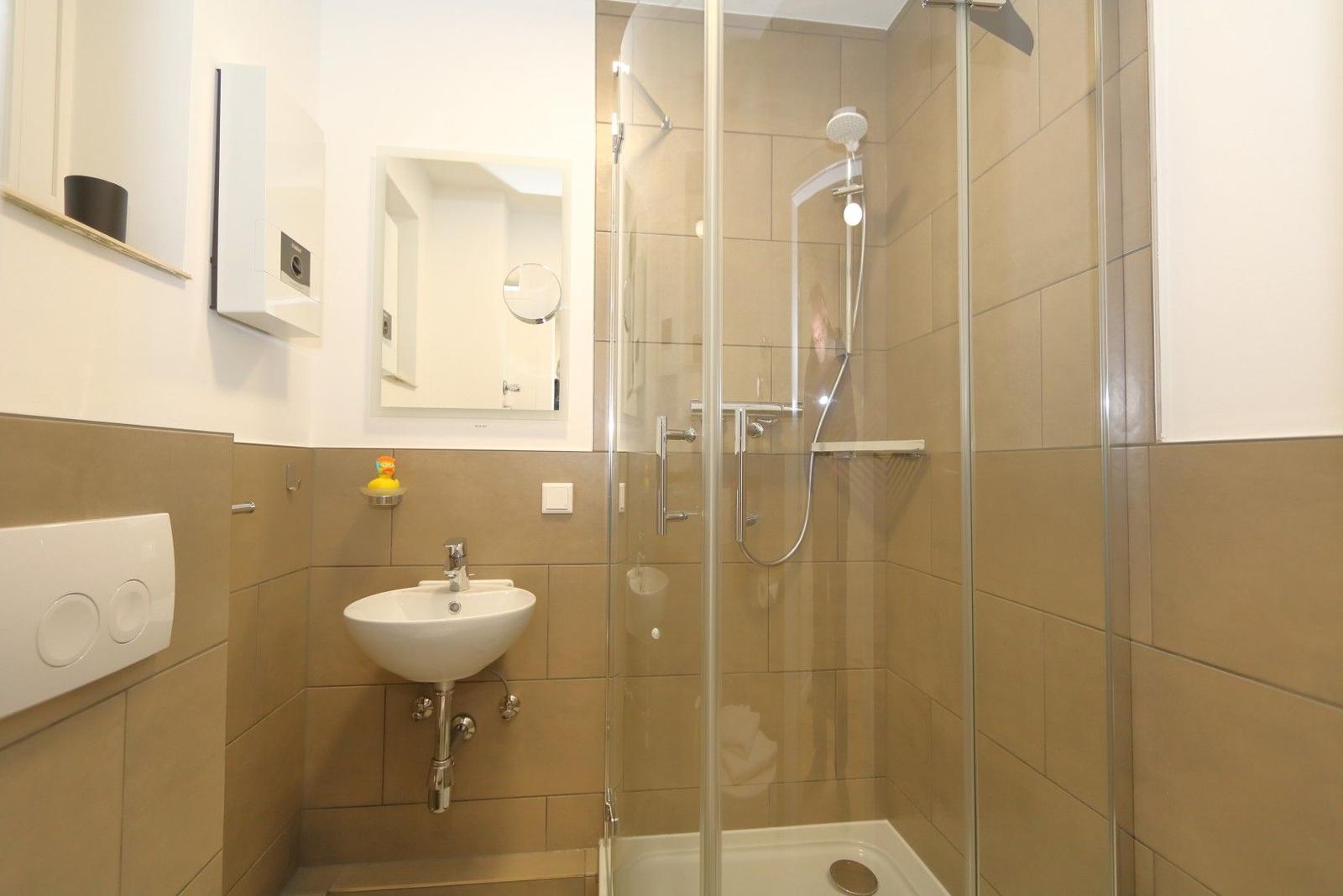 Bad mit Dusche, Waschbecken und Spiegel