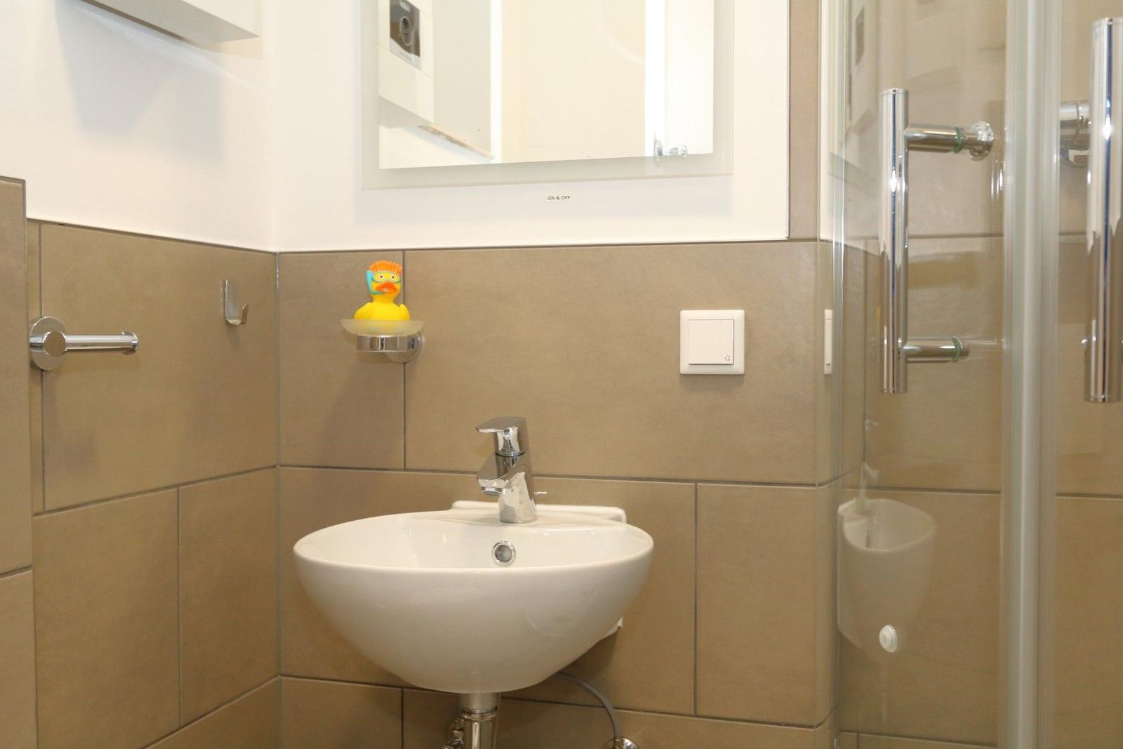 Badezimmer mit Waschbecken, Dusche und gelbem Schwimmring