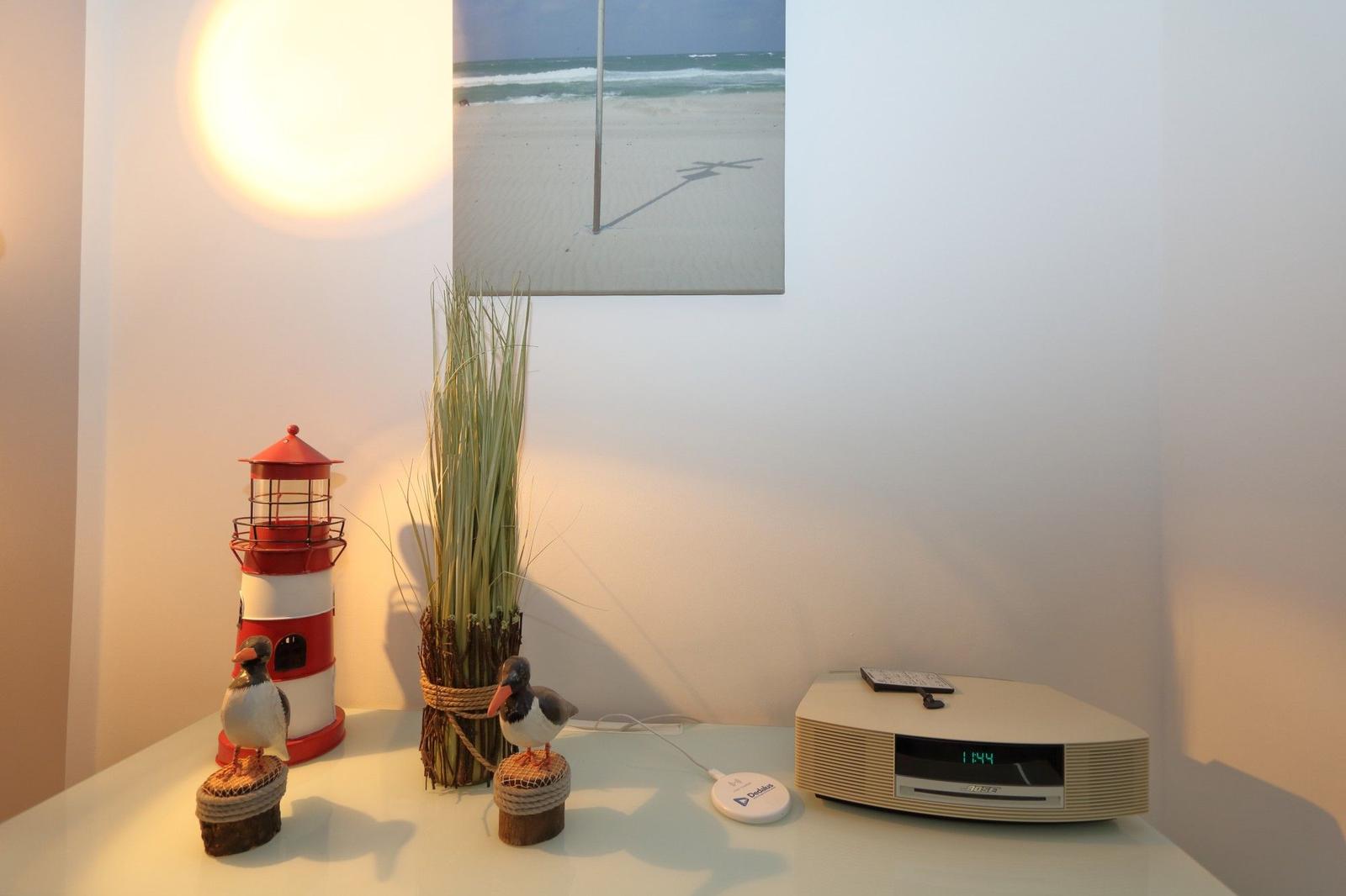 Tisch mit Lautsprecher, Strandbild, Laterne und Vogeldekoration.