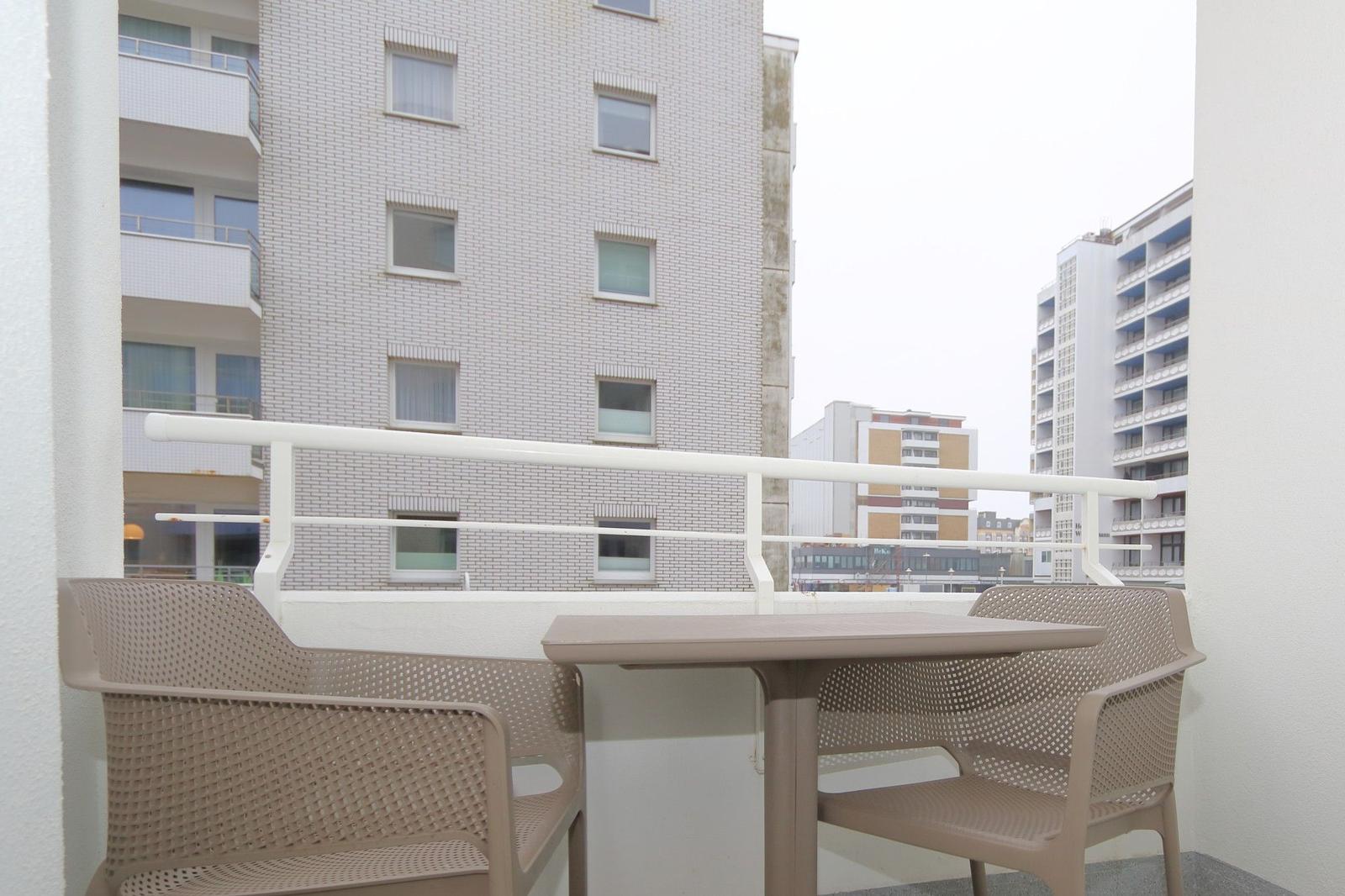 Balkon mit Tisch und zwei Stühlen, Blick auf Hochhäuser