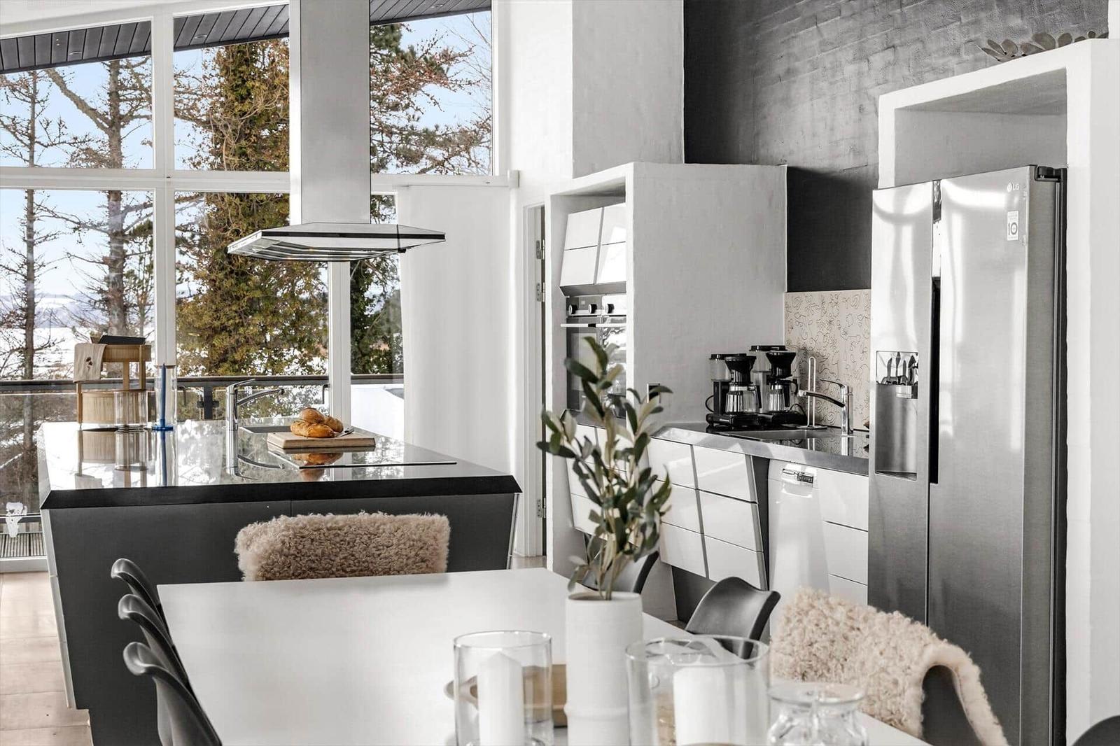 Moderne Küche mit Essbereich und Blick auf Wald und Berge.