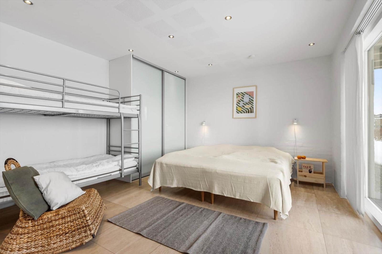 Schlafzimmer mit Doppelbett und Kletterbett, großes Fenster und moderner Schrank.