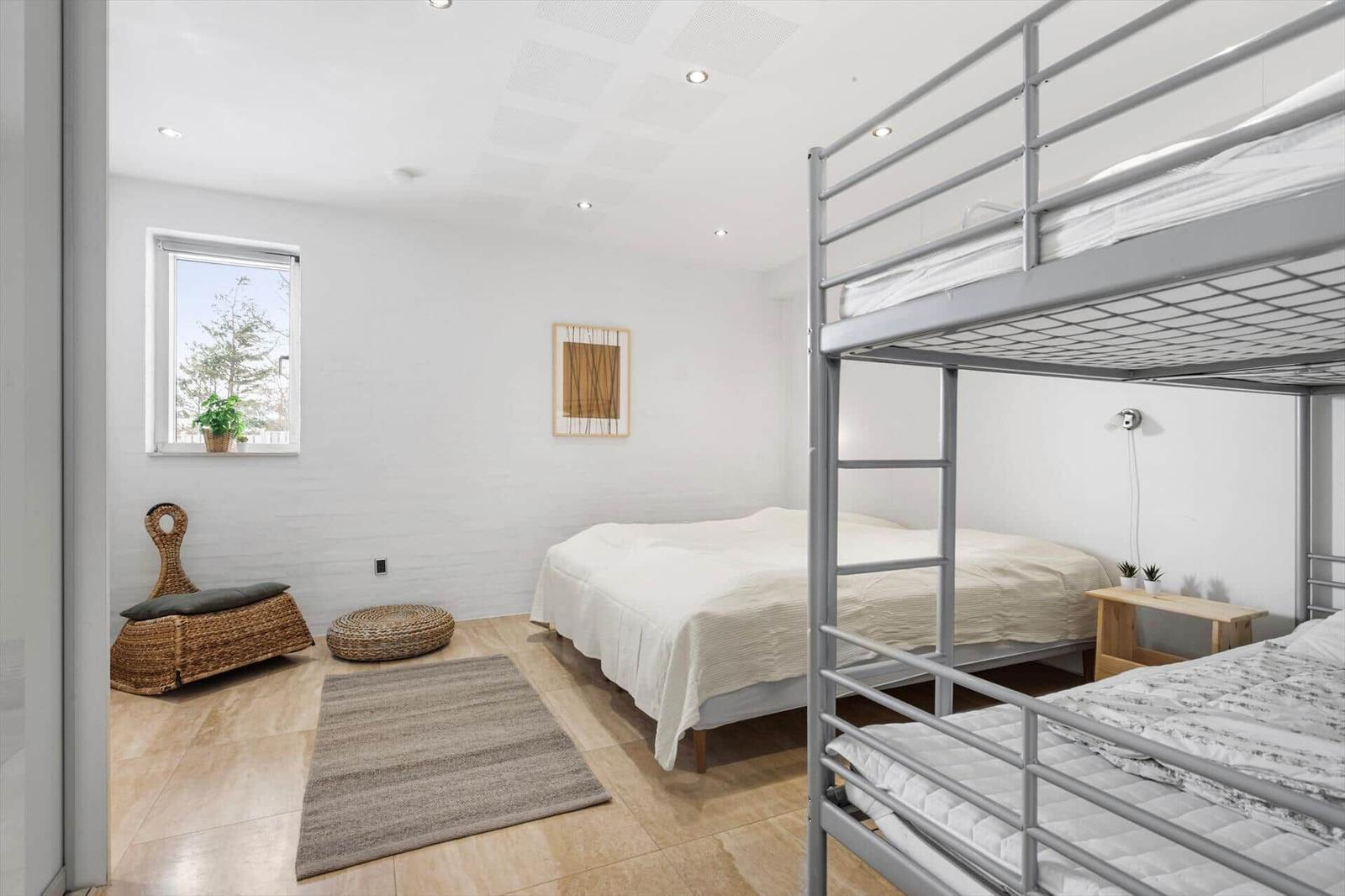 Schlafzimmer mit Doppelbett und Kletterkorb. Fenster, Teppich und Wandbild sichtbar.
