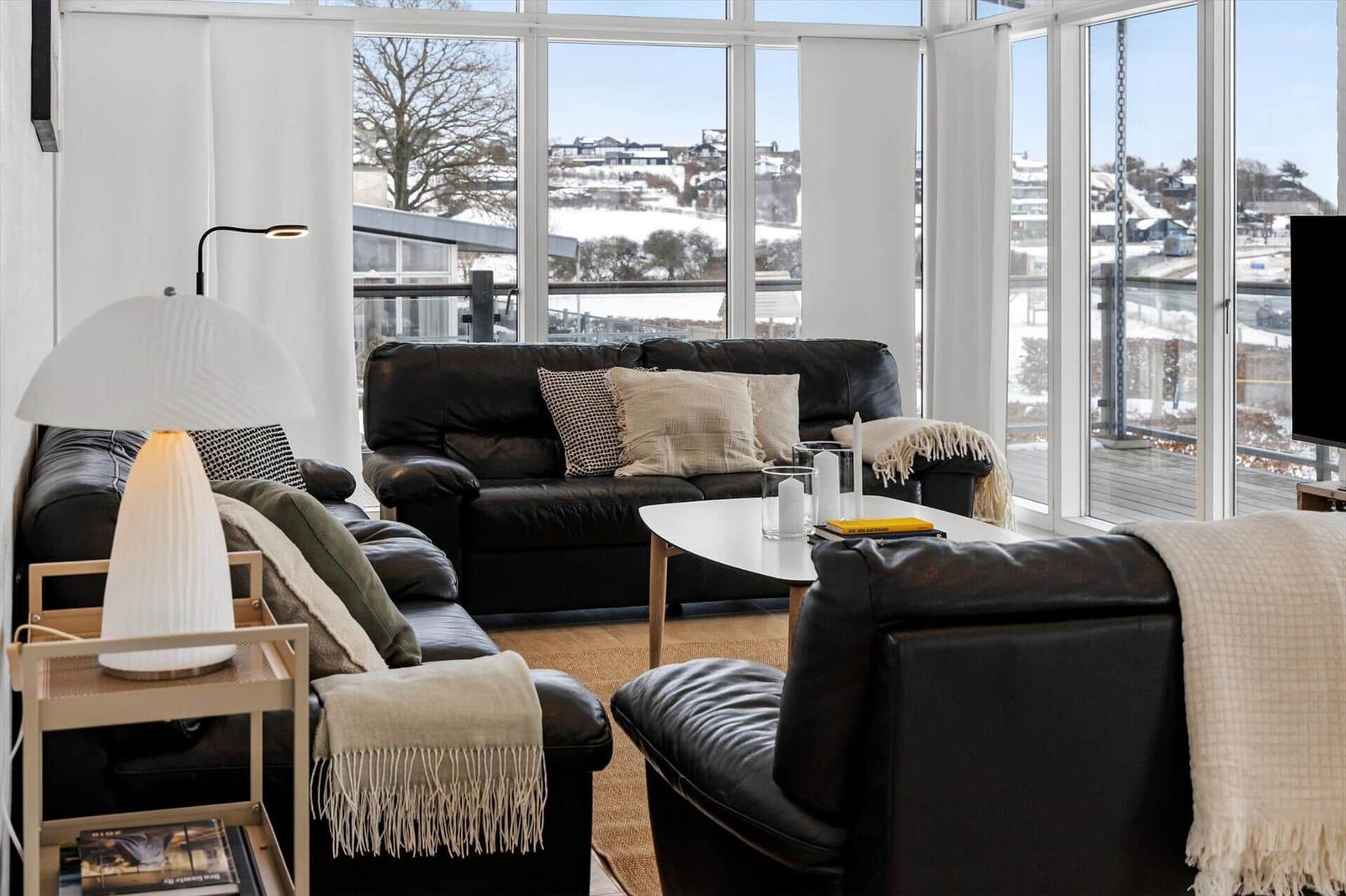 Wohnzimmer mit Ledersofa, Couchtisch und großem Fensterblick.