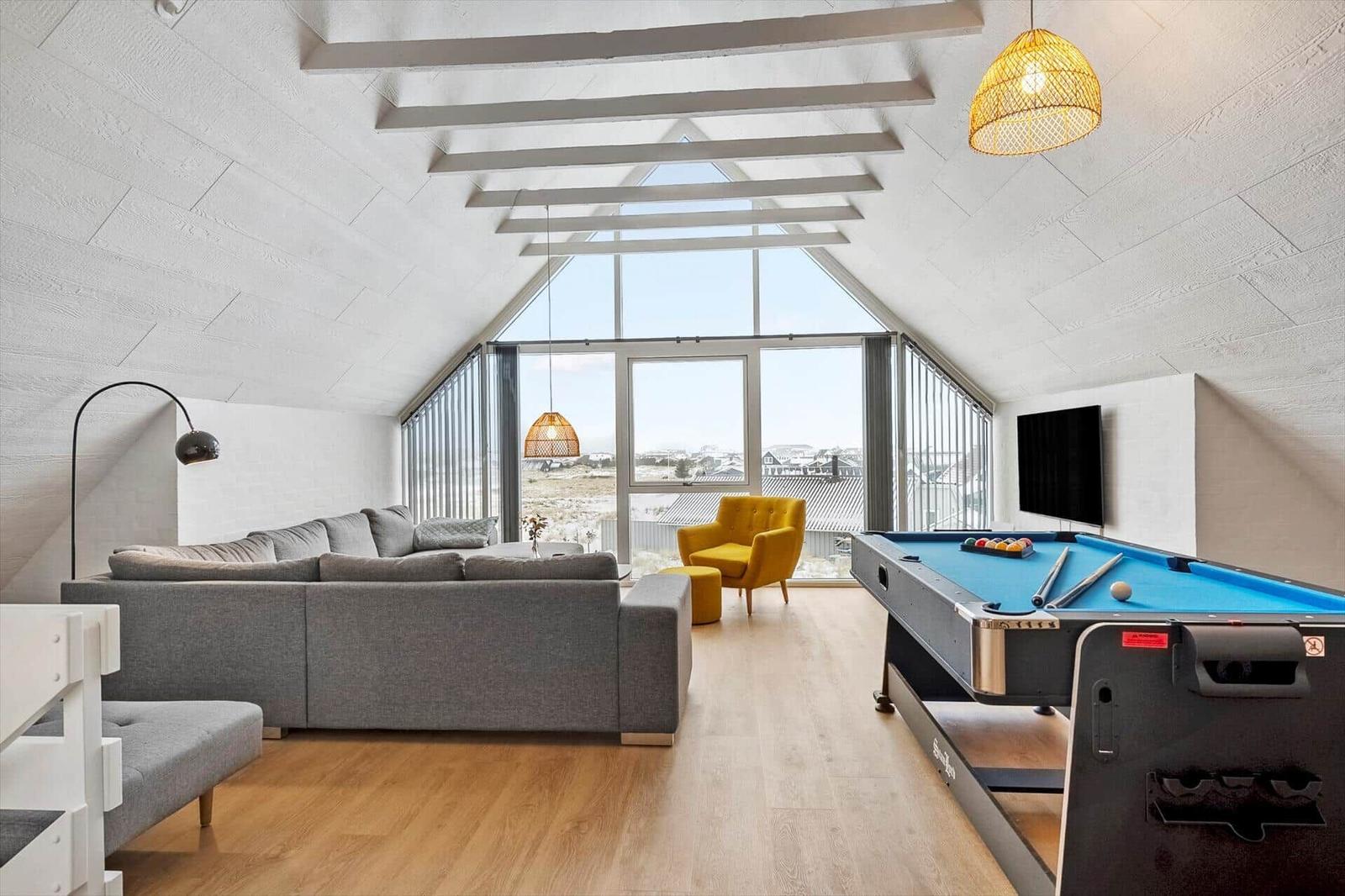 Wohnraum mit Pooltisch, Sofa und großem Fensterblick.