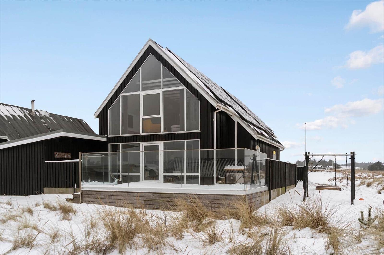 Moderne Villa mit Glasfassade und Terrasse im Schnee.