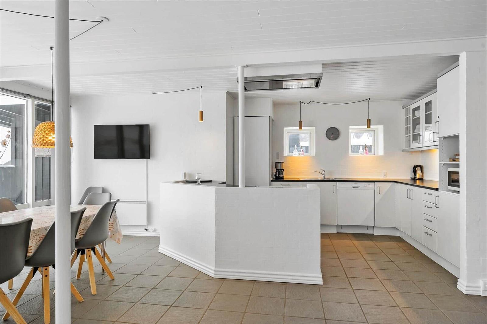Küche mit Essbereich und Fernseher. Weiße Arbeitsplatten und Schränke.