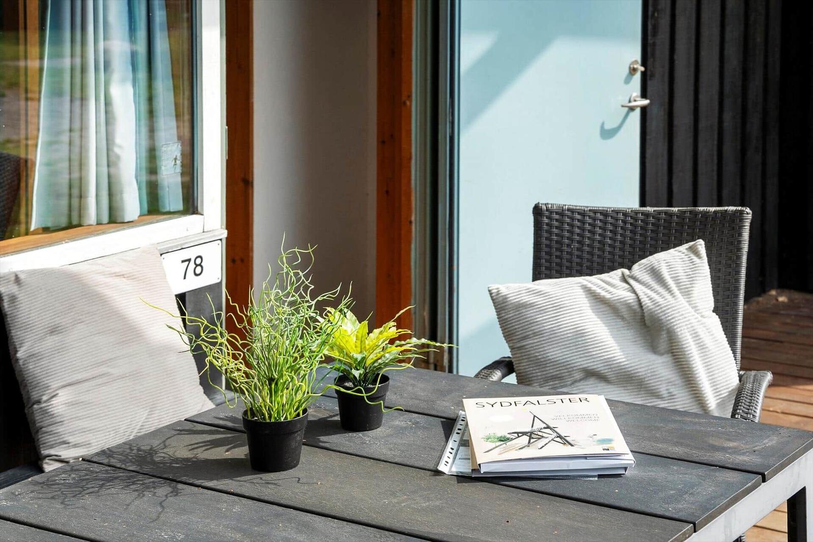 Terrace with table, chairs, and plants. A book lies on the table.
