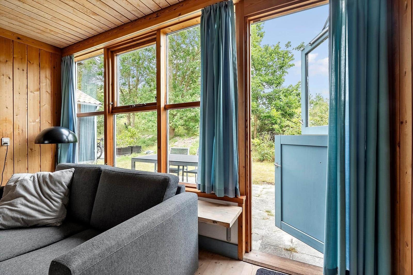 Living room with sofa, wooden wall, and view of garden