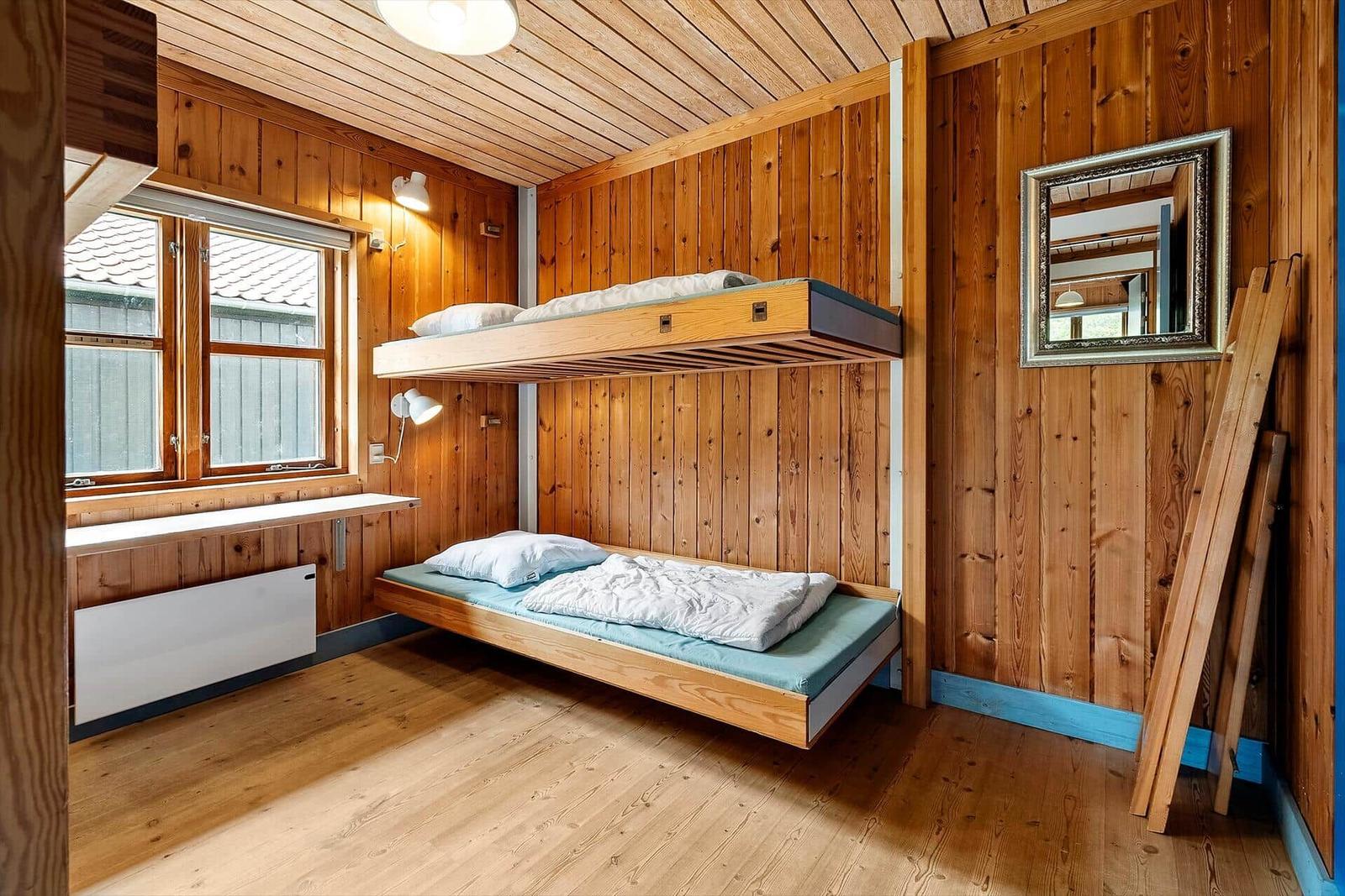 Room with two mattresses, wooden walls, and window.