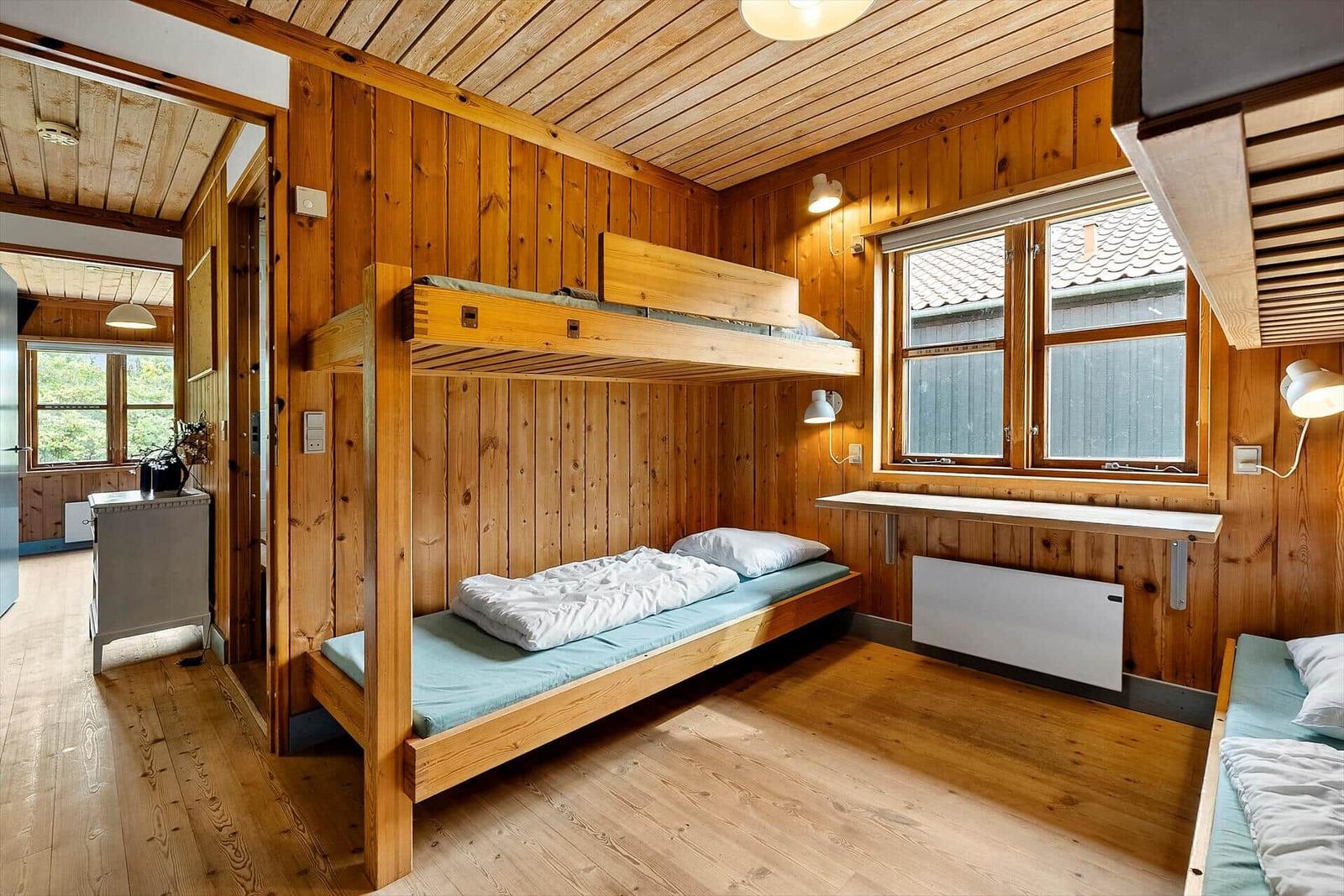 Room with wooden walls, bunk beds, and window
