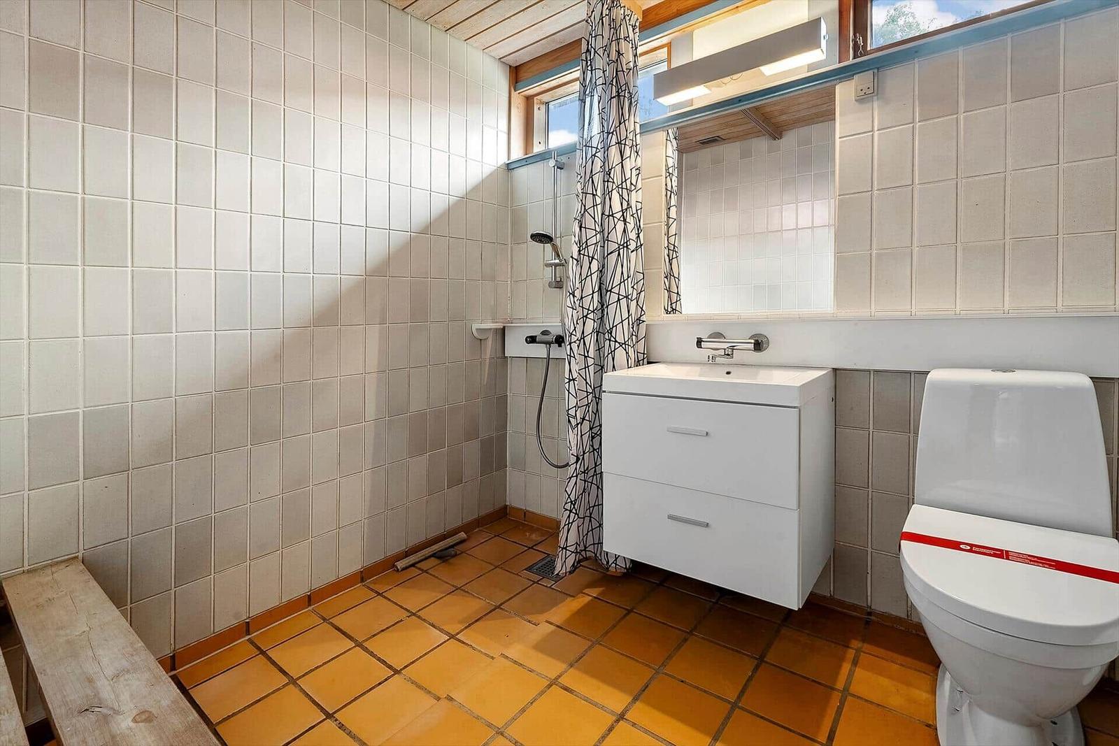 Bathroom with shower, sink and toilet. Tile floor and walls.