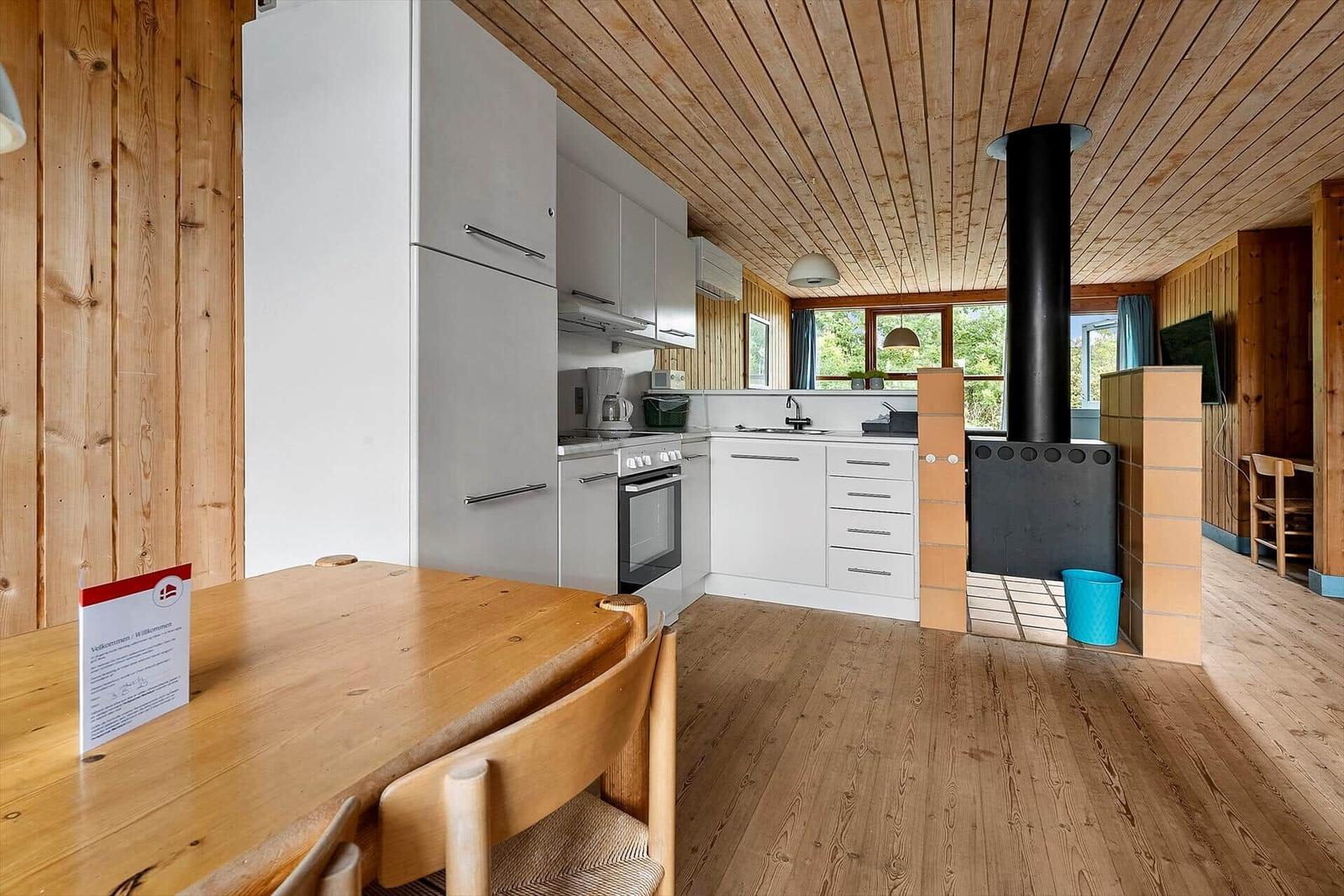 Kitchen with wooden walls, white built-in appliances, and wood stove