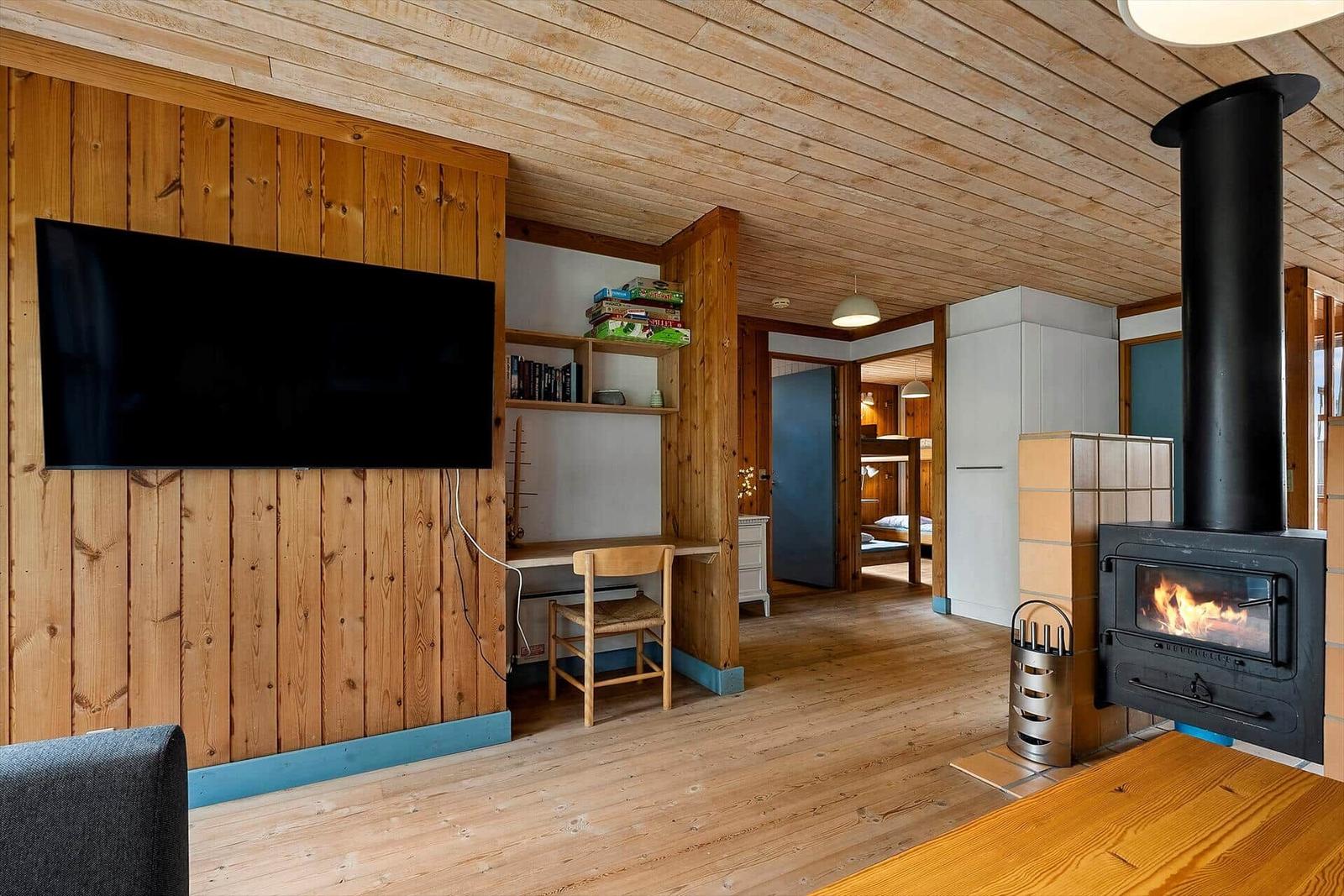 Living room with fireplace, TV, and desk. Corridor to the bedroom.