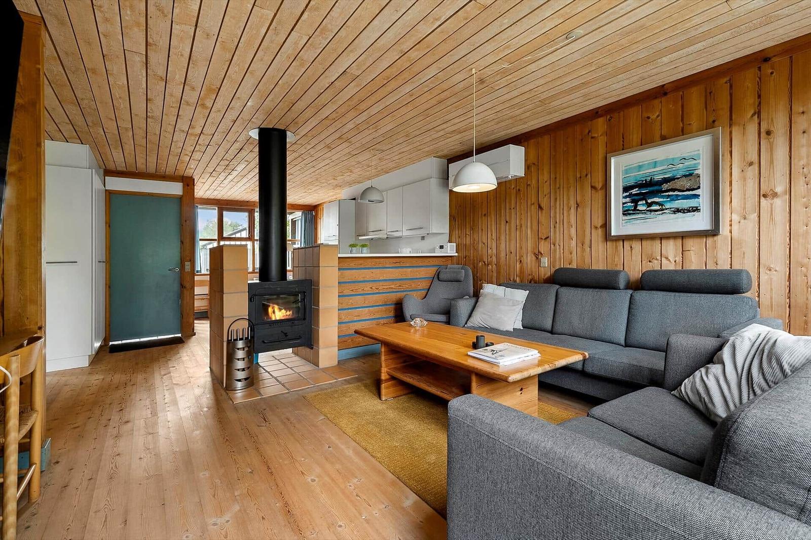 Living room with fireplace, sofa, and kitchen area