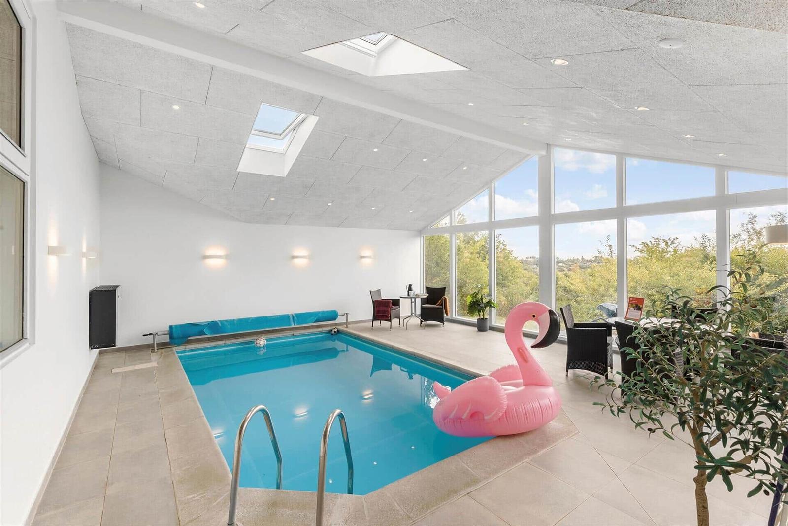 Innenpool mit pinkem Flamingo, großflächigen Fenstern und Dachfenstern.