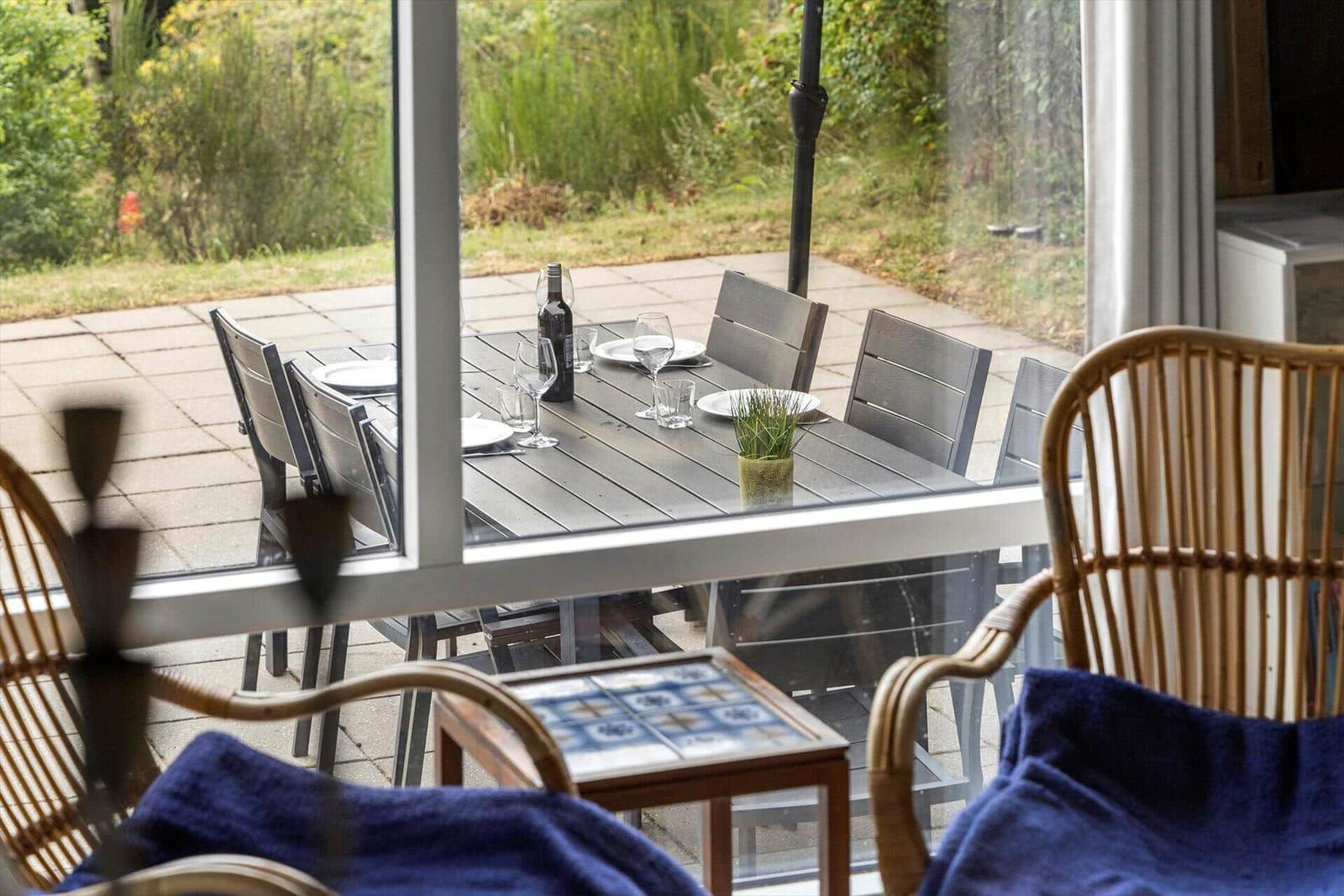 Durchsichtiges Fenster zeigt gedeckten Tisch mit Stühlen auf Terrasse.