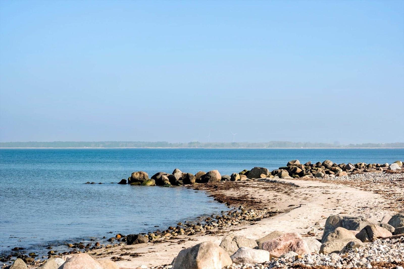 Strand mit Steinen und ruhigem Meer im Hintergrund
