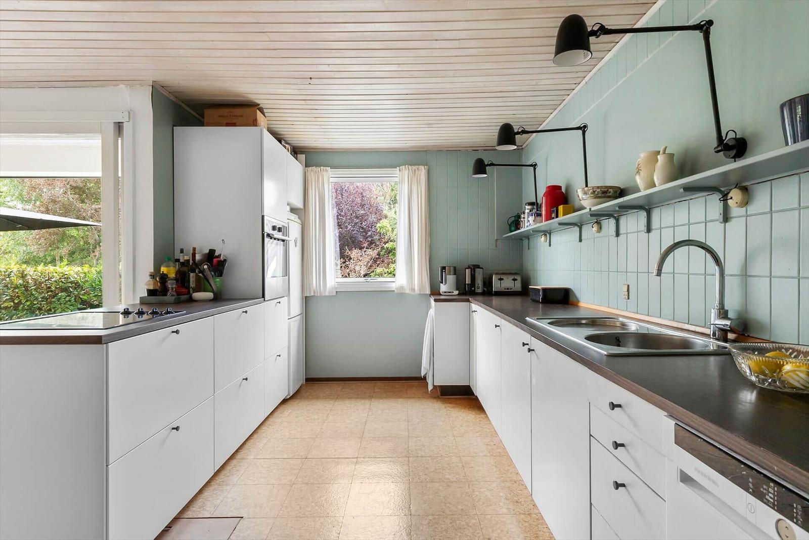 Kitchen with white cabinets, green walls, and dark wood countertops.