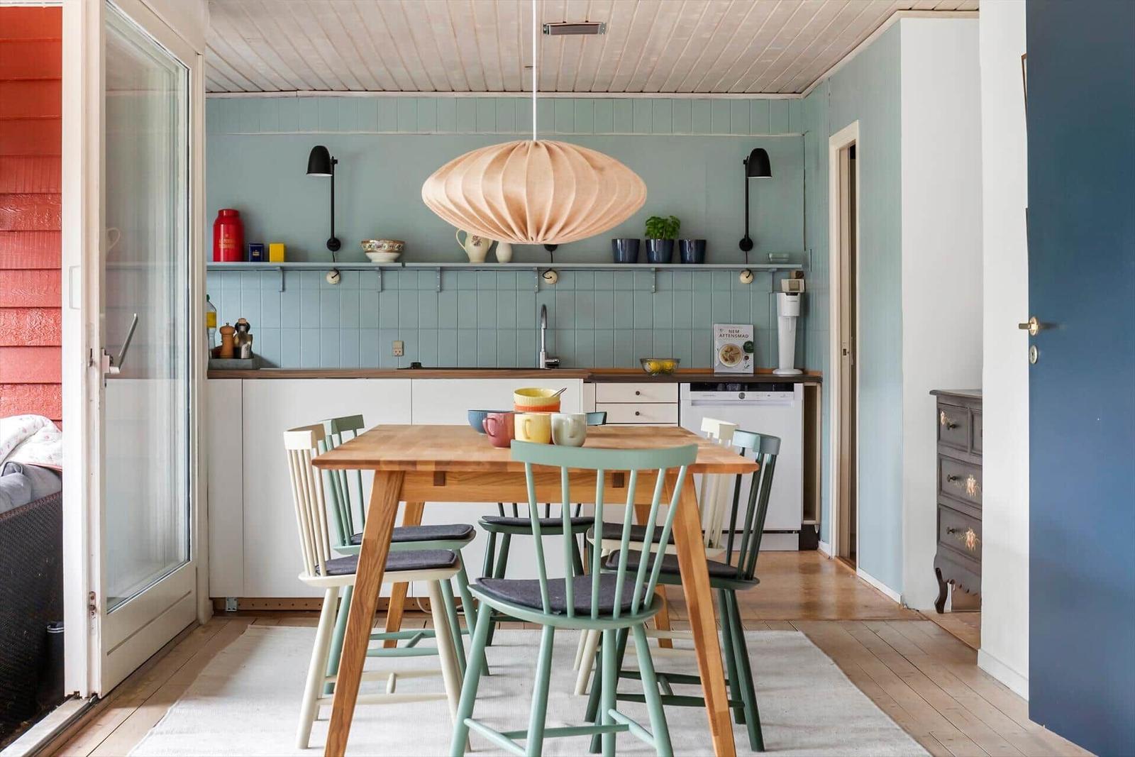 Kitchen with dining area, wooden table, chairs, and pendant light.