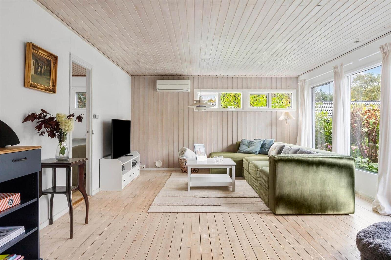 Living room with green sofa, wooden floor, and large windows.