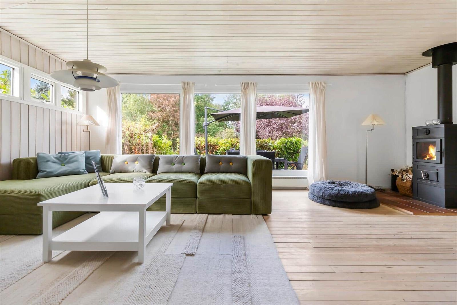 Living room with green sofa, fireplace, and large window to outdoor terrace.