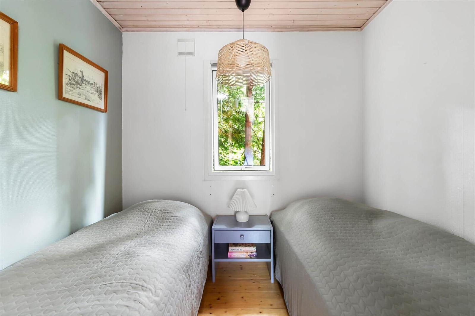 Two beds with mattresses and a nightstand with a lamp.