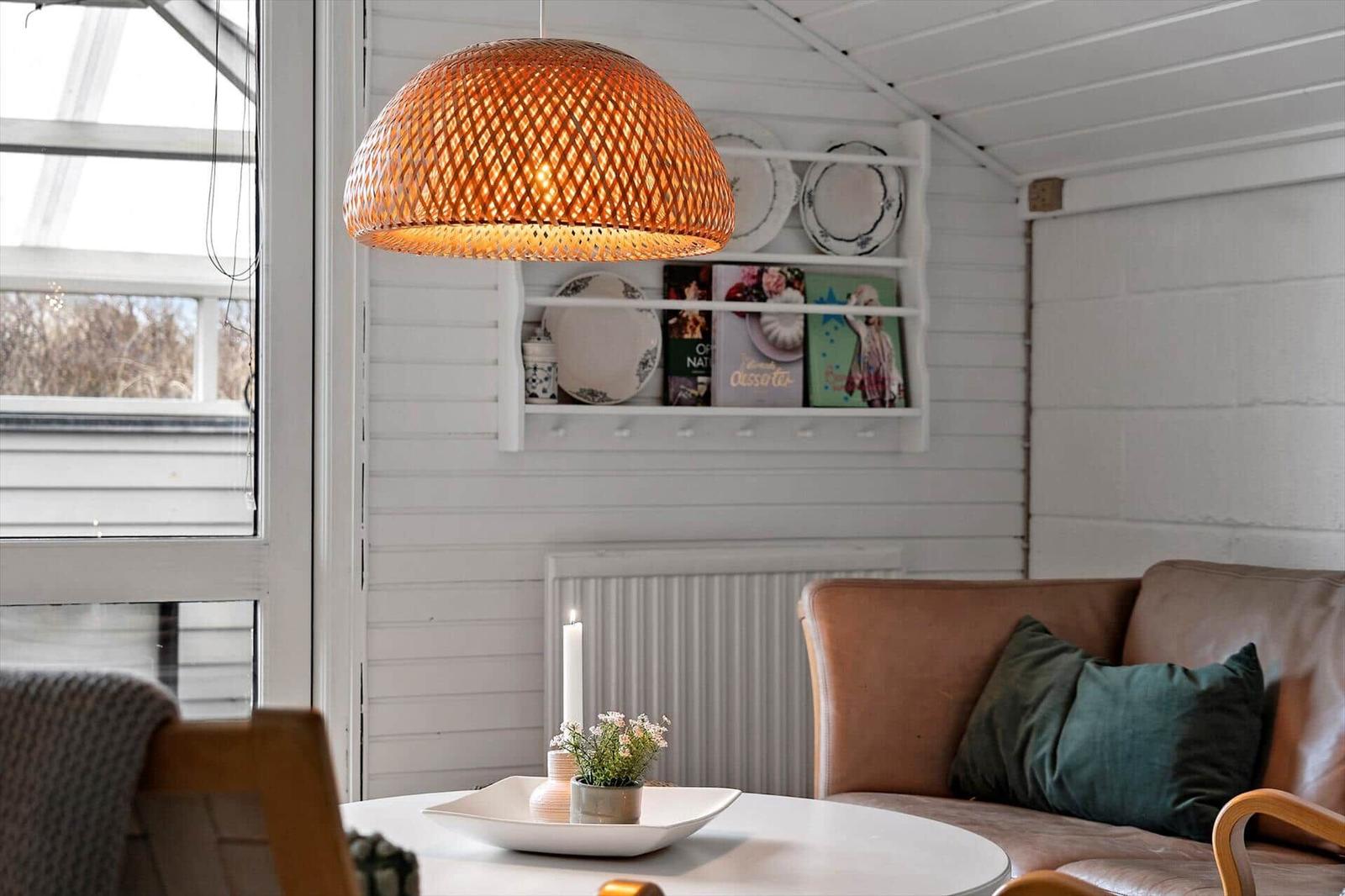 Ein Raum mit braunem Sofa, weißer Wand und runden Tisch mit Lampe.