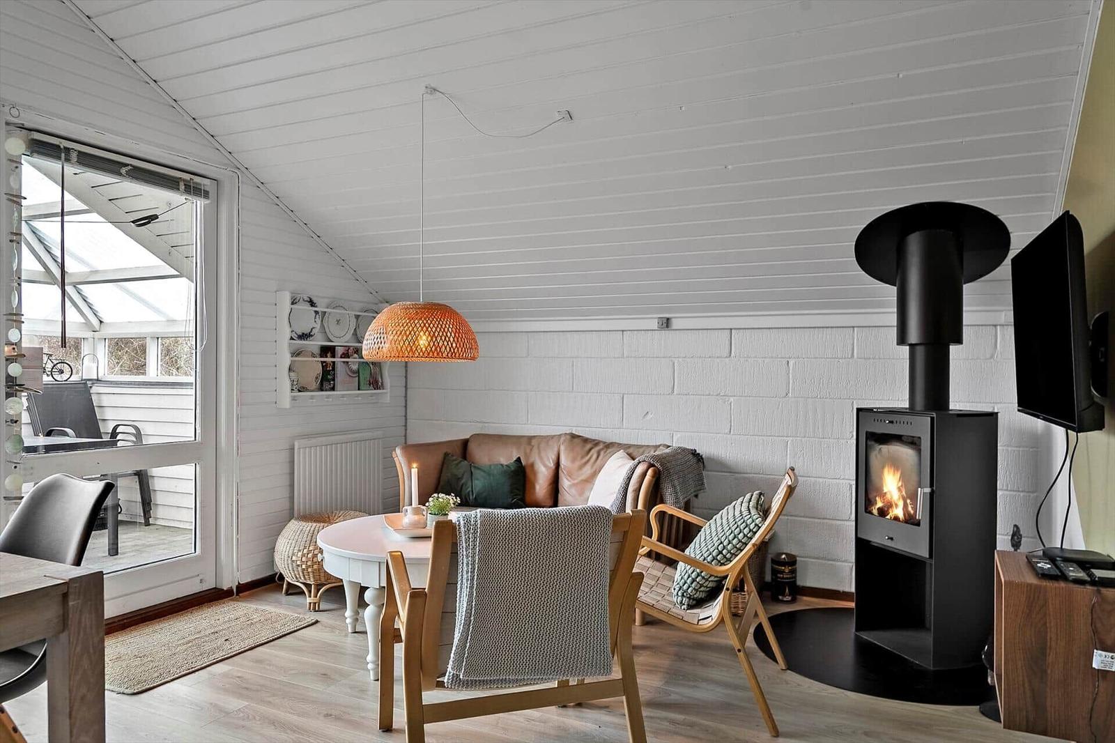 Wohnzimmer mit Sofa, Kamin und Esstisch. Durchgang zur Terrasse.