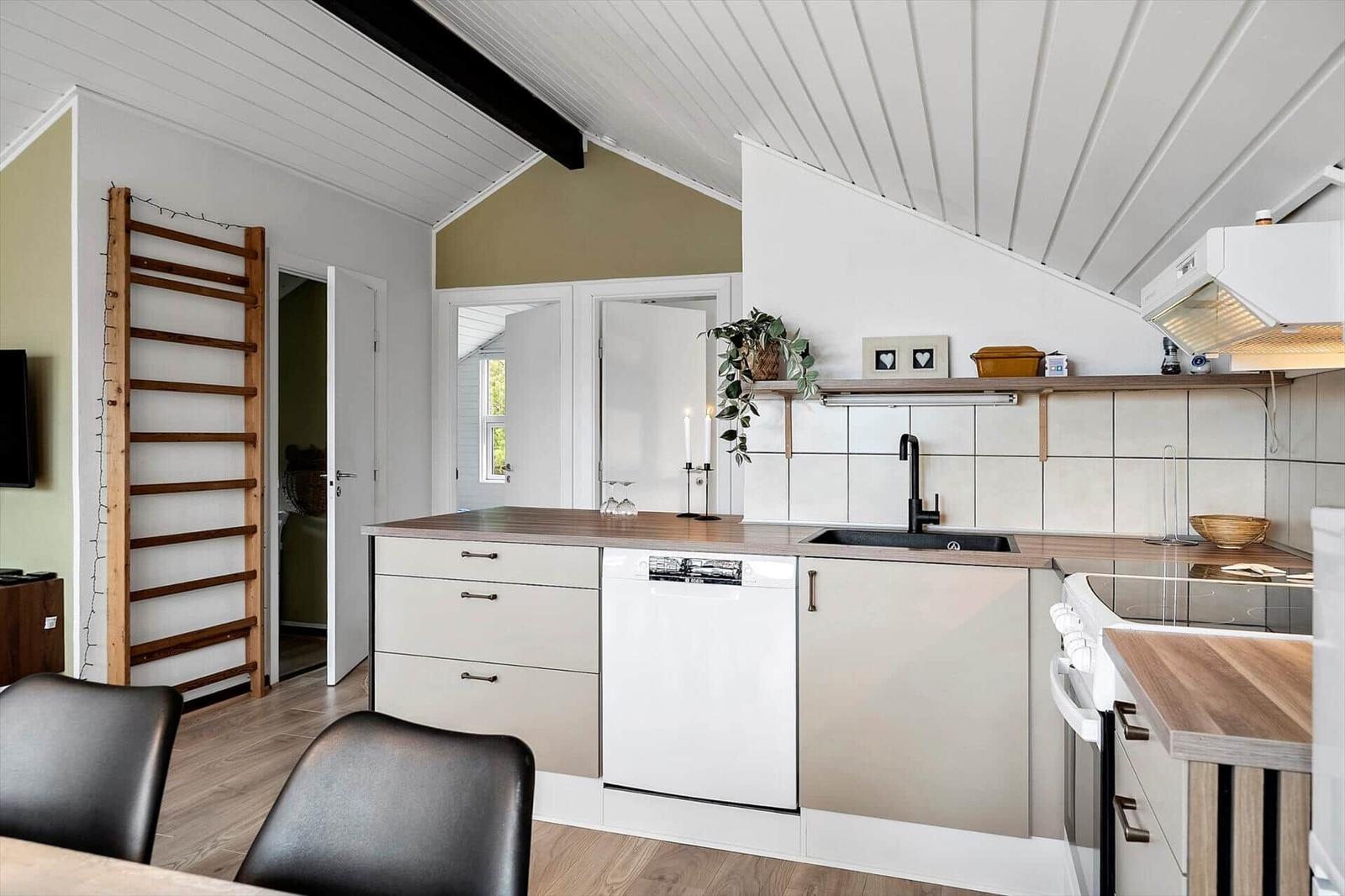 Küche mit Holz Arbeitsplatte, Spüle und Backofen unter schrägem Dach.