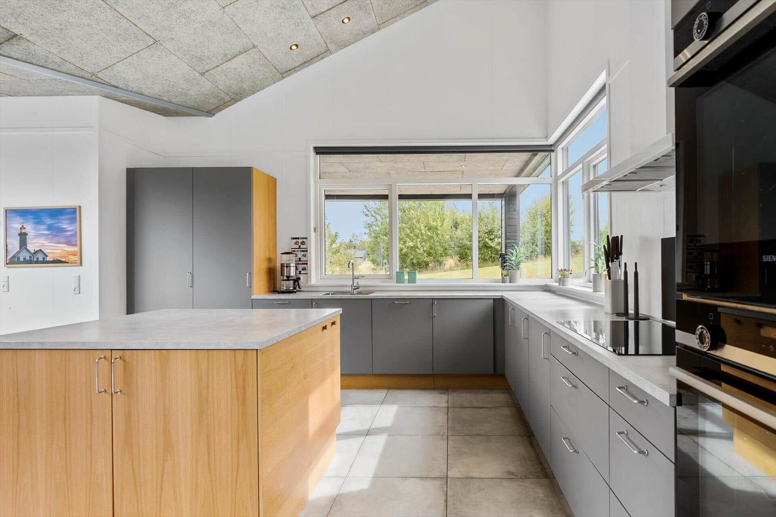 Moderne Küche mit Kücheninsel, Fenster und Geräten.