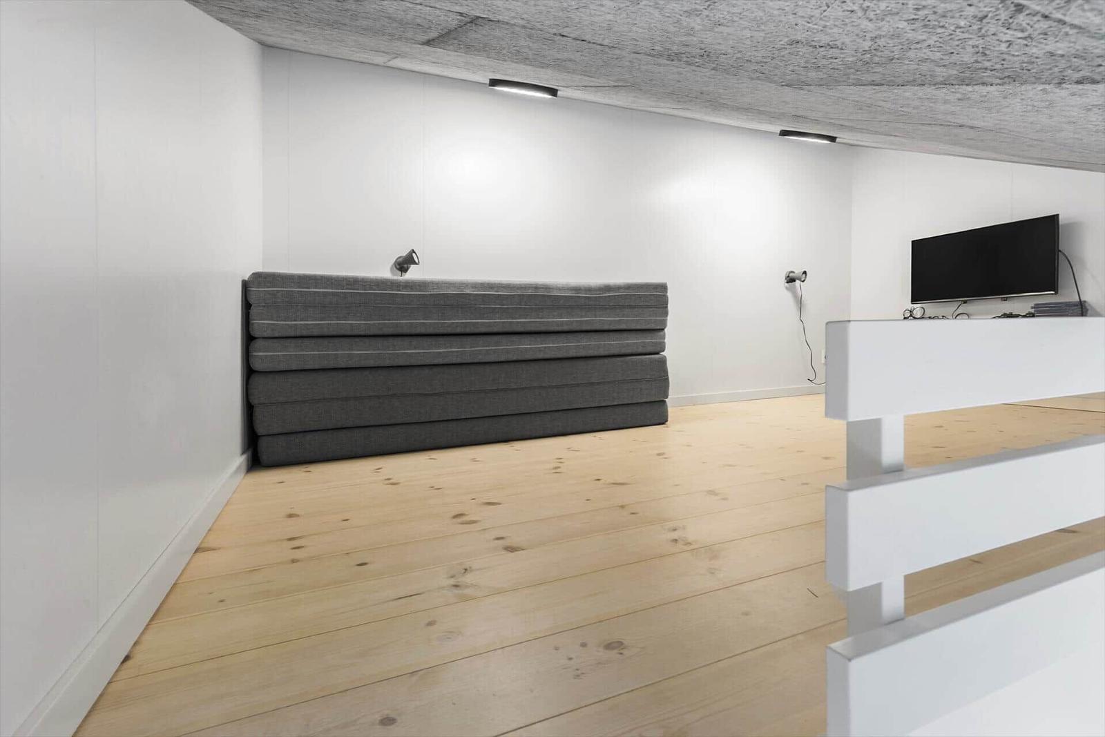 Raum mit grauem Sofa, Fernseher und Holzboden
