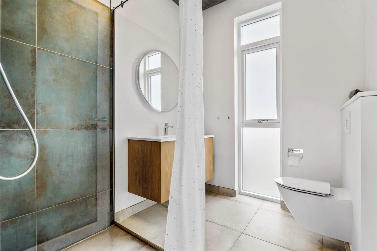 Badezimmer mit Dusche, Waschbecken und Toilette.