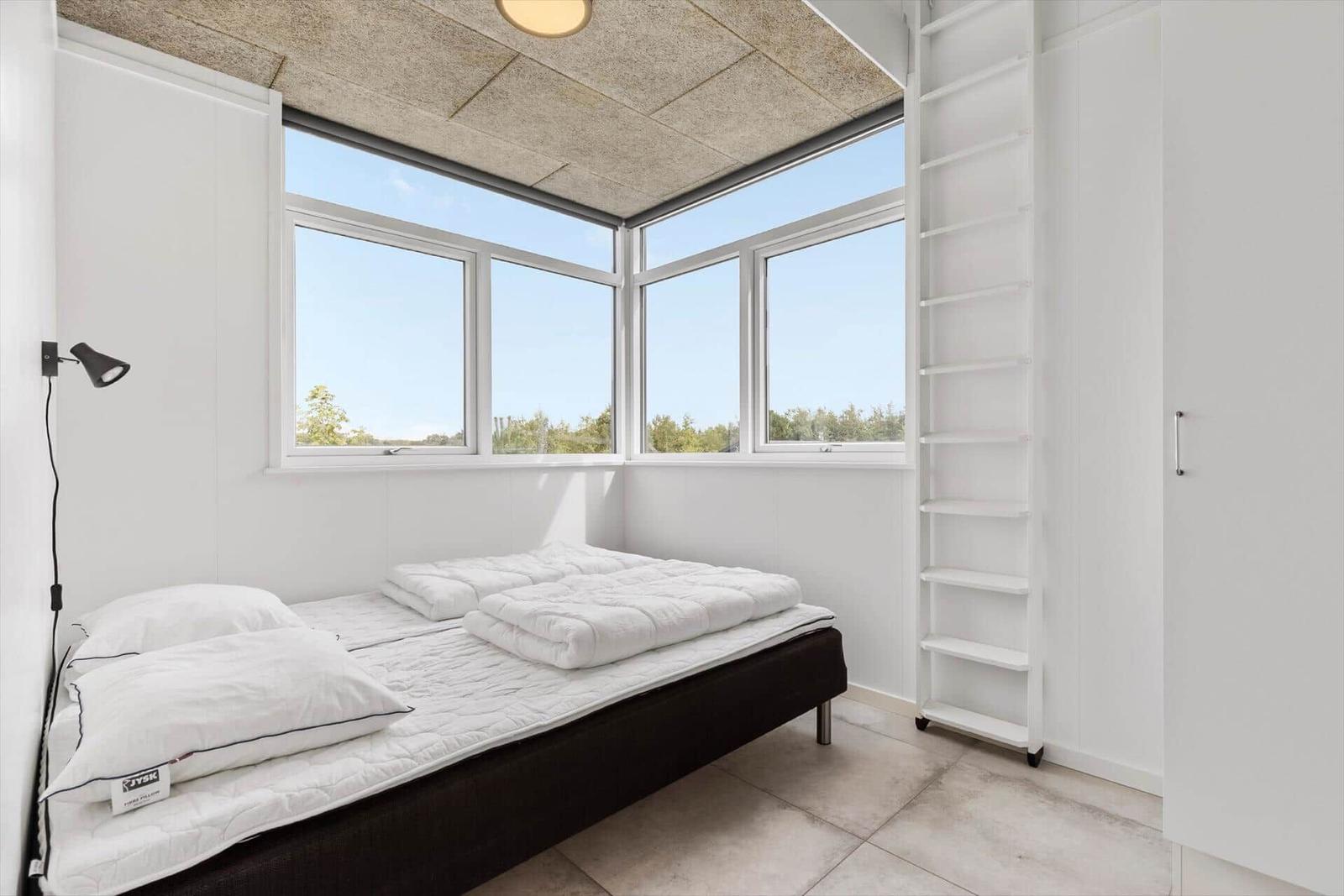 Schlafzimmer mit großem Fenster und Doppelbett.