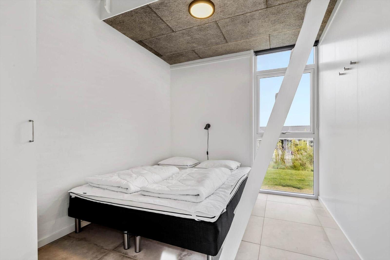 Schlafzimmer mit Bett, Fenster und Betondecke.