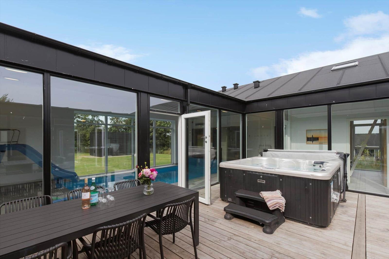 Terrasse mit Hot Tub, Esstisch und Blick auf Pool und Garten.