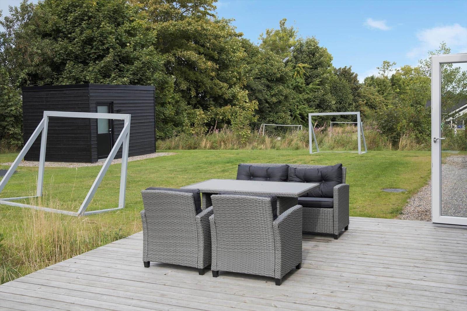 Terrasse mit Sitzgruppe, Fußballtoren und kleinem Haus im Garten.