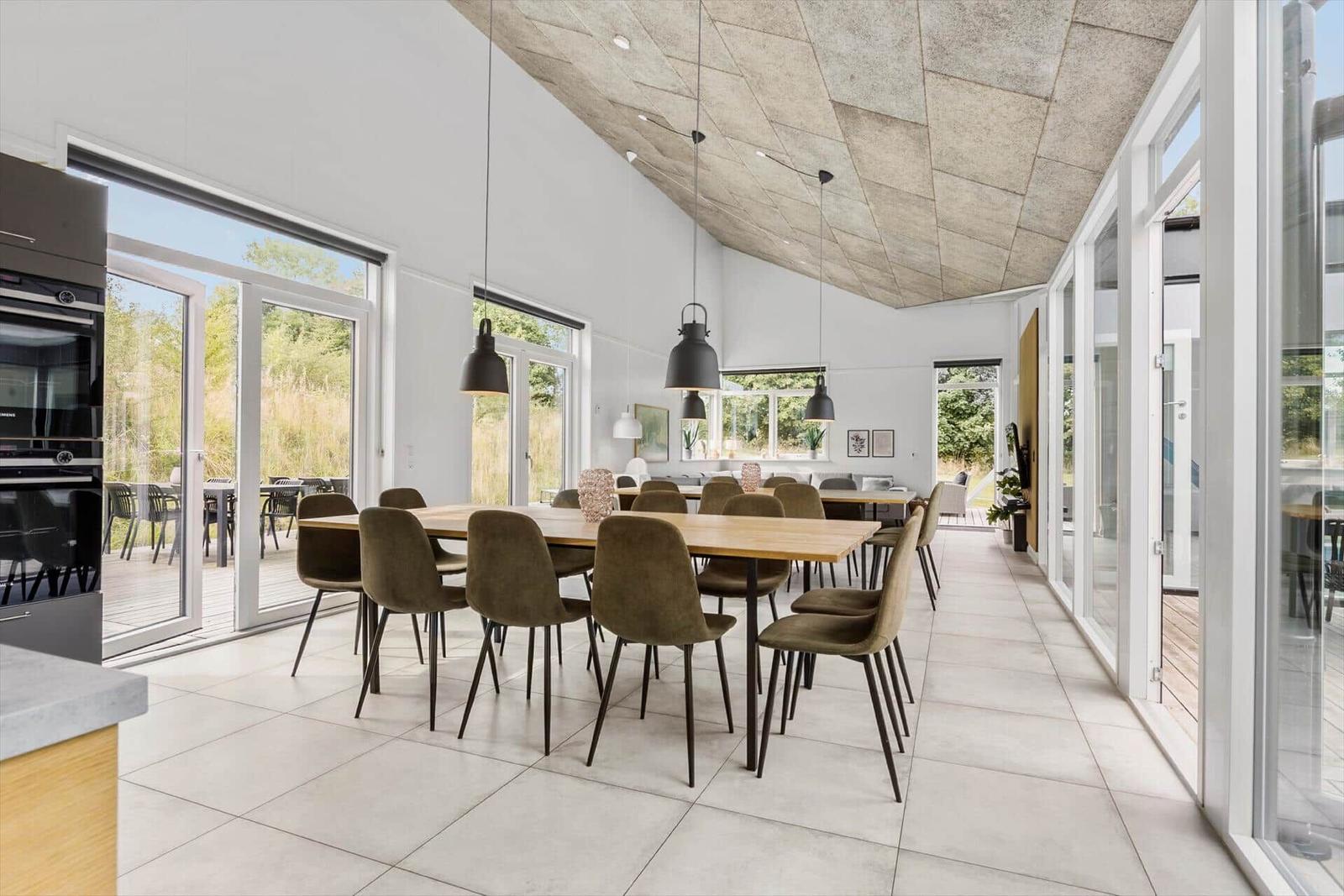 Großer Essbereich mit Holztisch, Stühlen und Glasfronten zur Terrasse.