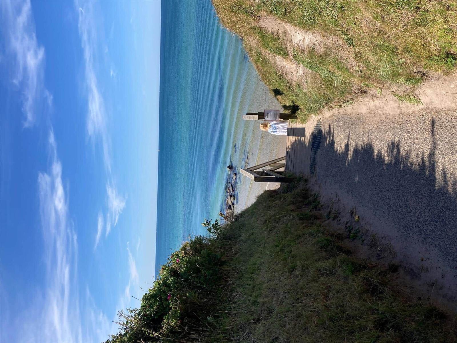View of the sea with a wooden staircase and a person on the beach.