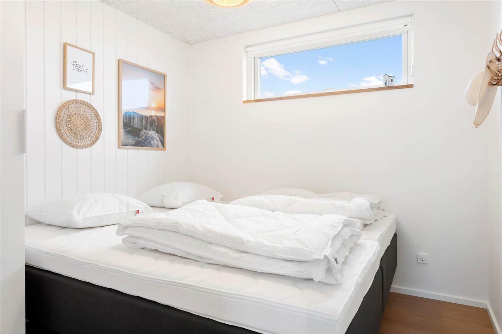 Schlafzimmer mit Bett, Fenster und Wanddekoration.