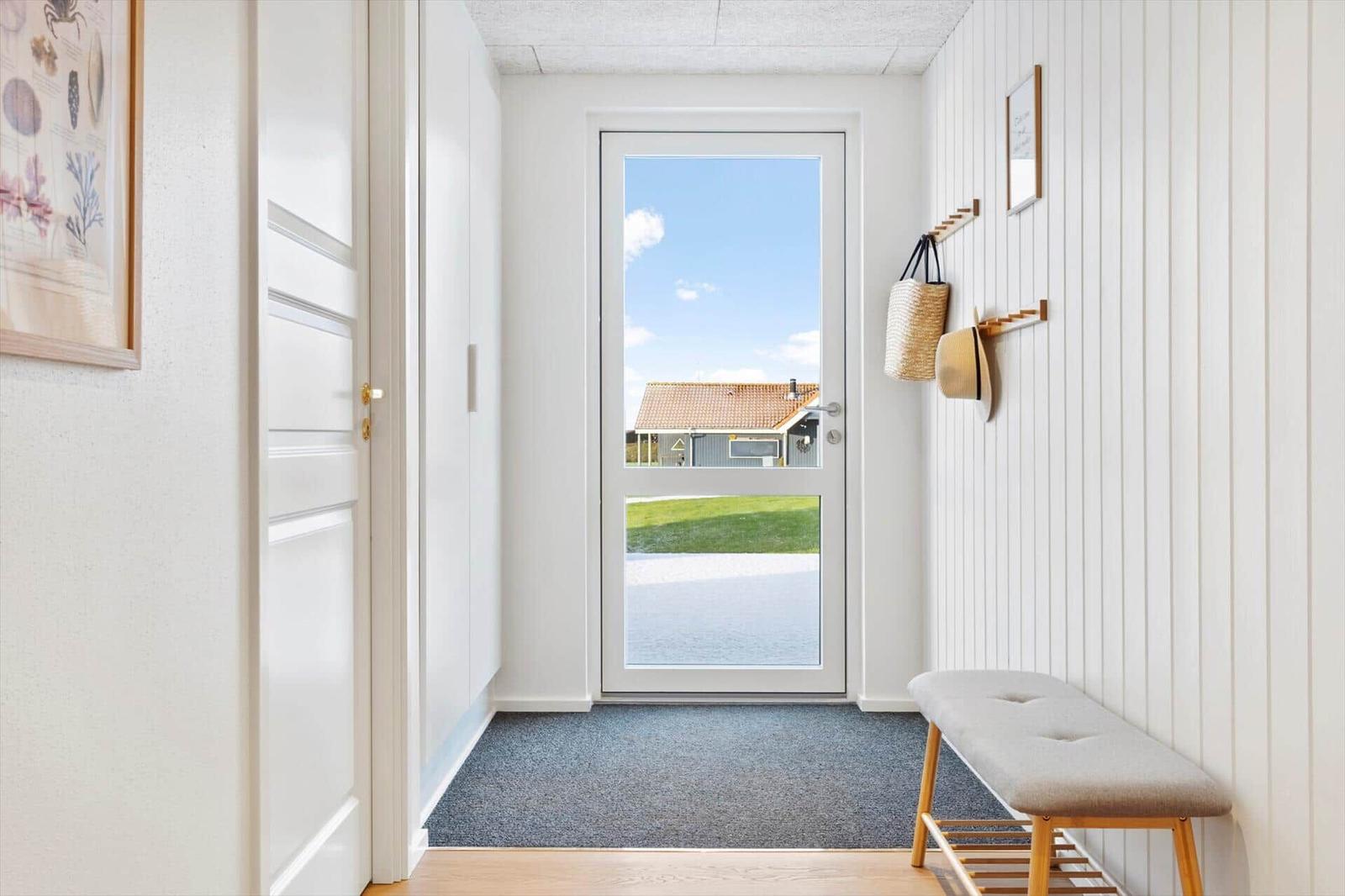 Eingangsbereich mit Tür zum Garten, Wandgarderobe und Sitzbank.