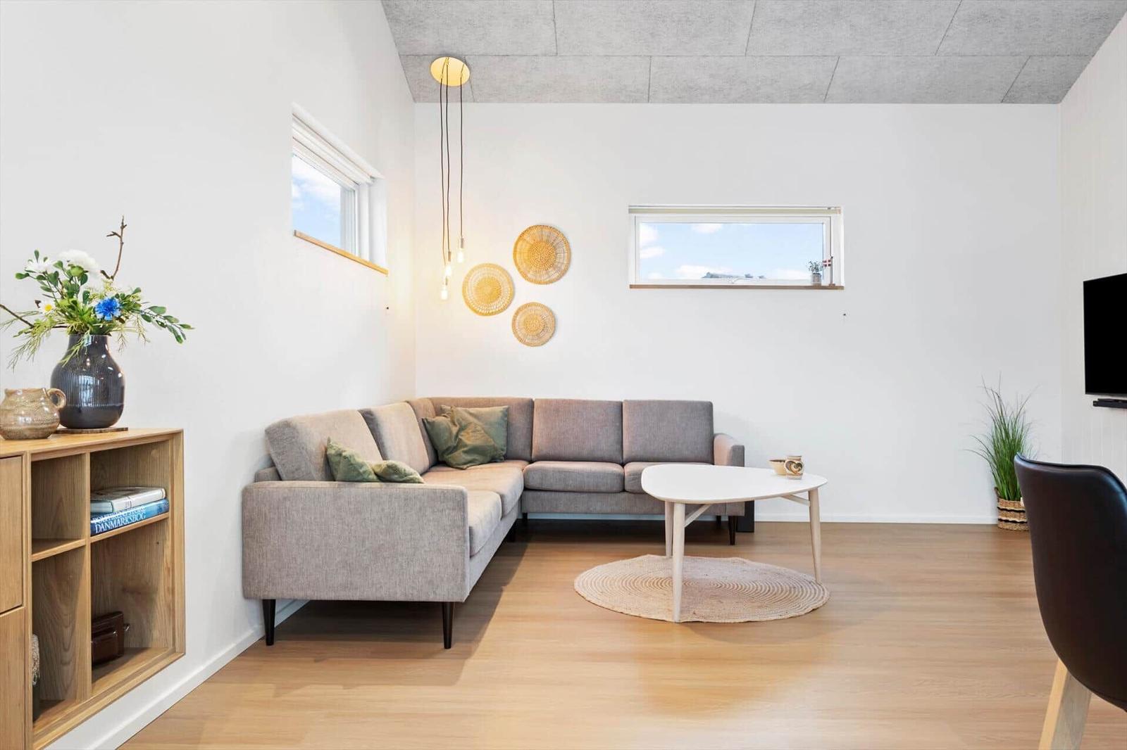 Wohnzimmer mit grauem Sofa, runden Tisch und Holzboden.