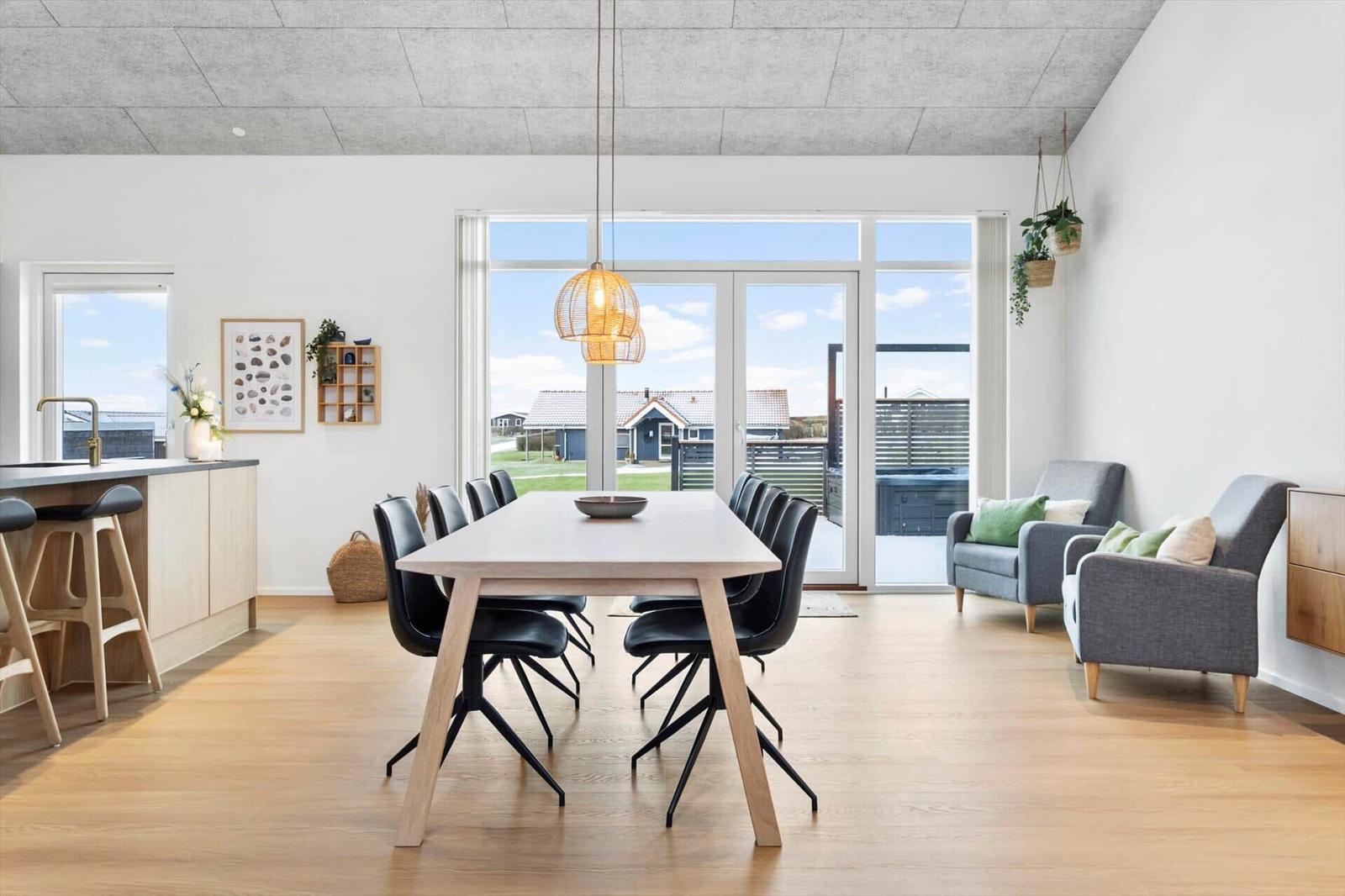 Essbereich mit Tisch und Stühlen, Wohnbereich mit Sofas und großem Fenster.