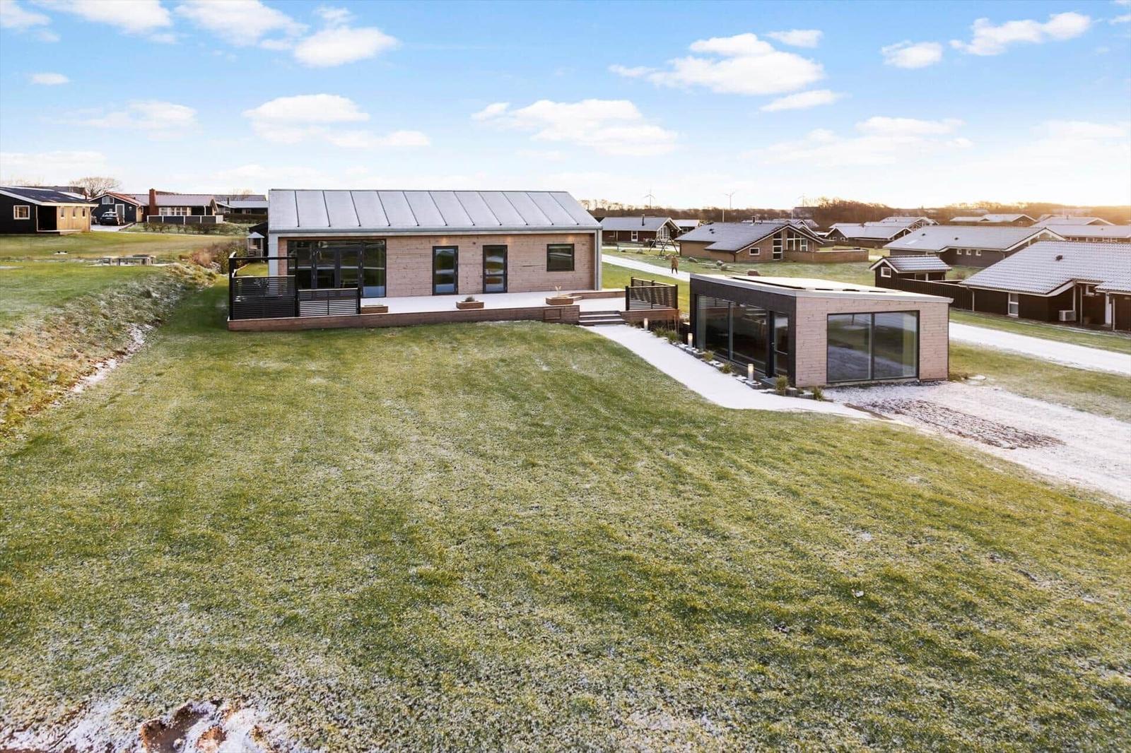 Moderne Villa mit großem Garten und Terrasse. Sonniger Tag mit klarem Himmel.