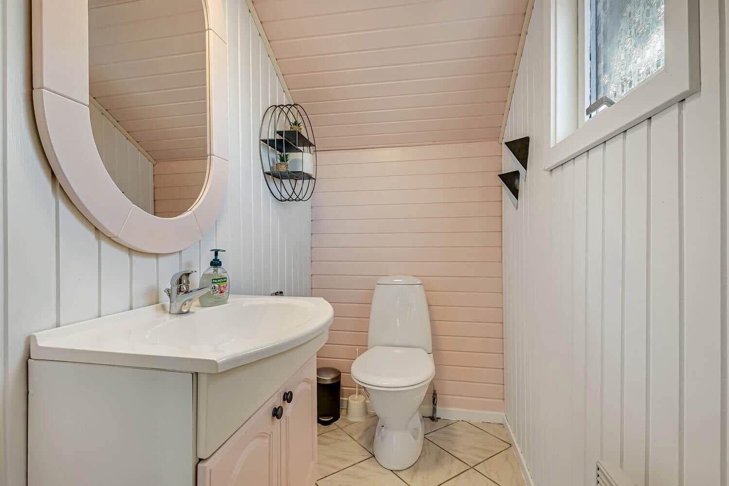 Badezimmer mit Waschbecken, Toilette und Spiegel an der Wand.