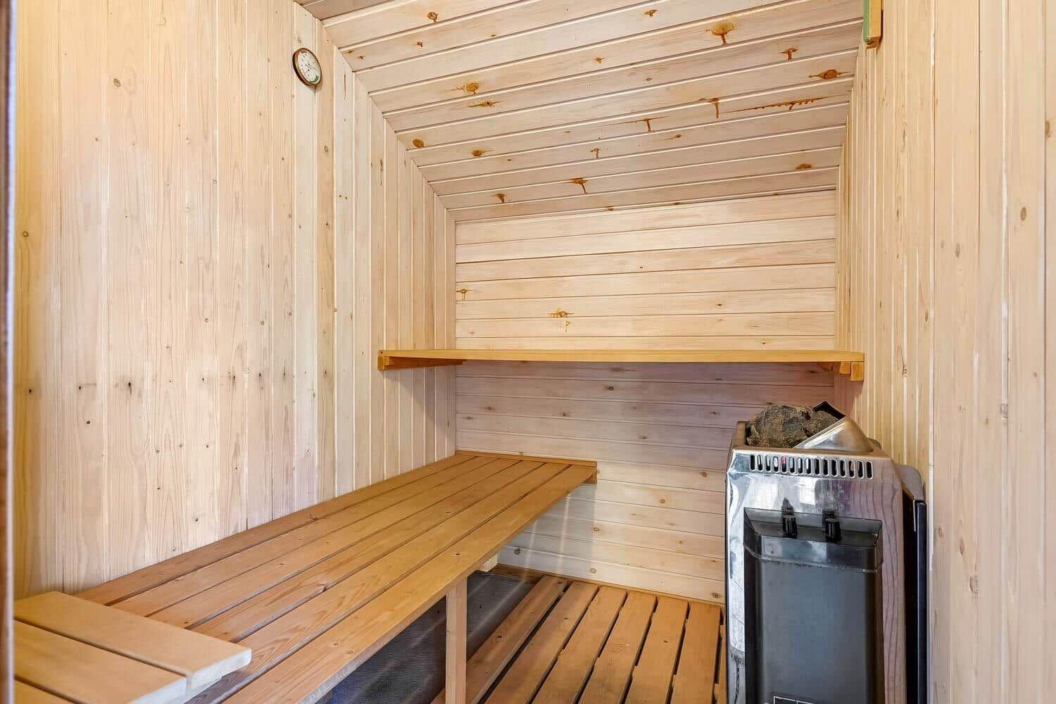 Sauna mit Holzbank, Heizung und Wanduhr.