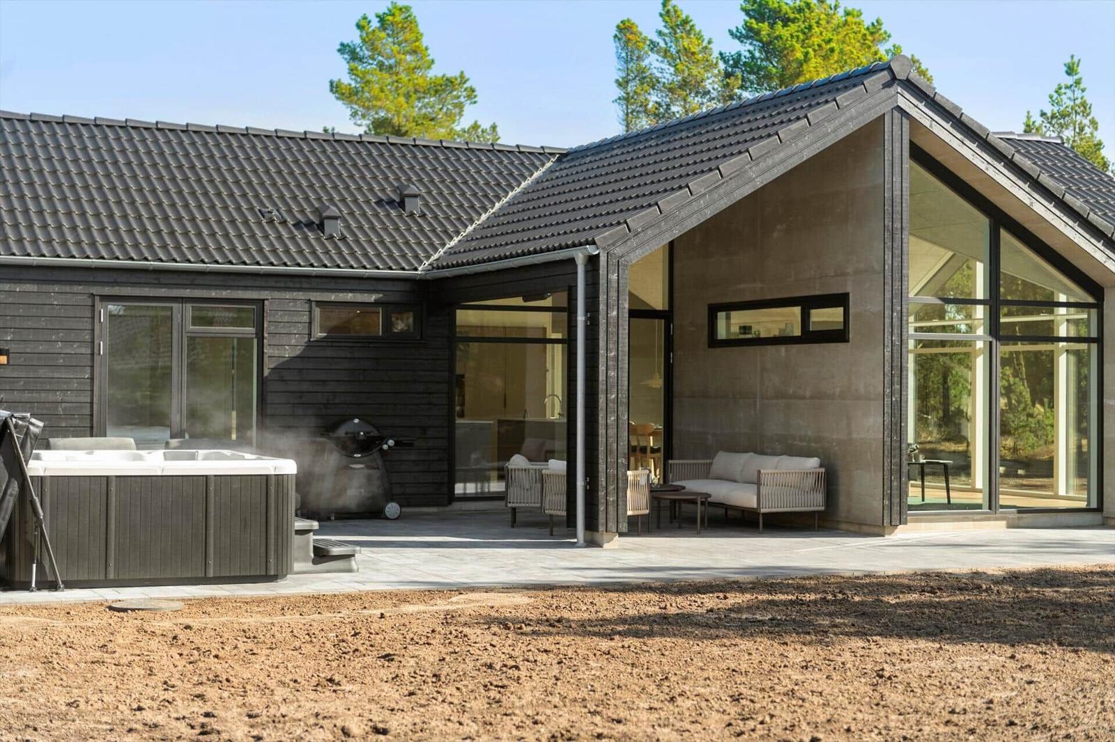 Modern villa with hot tub, grill, and large terrace with seating areas.